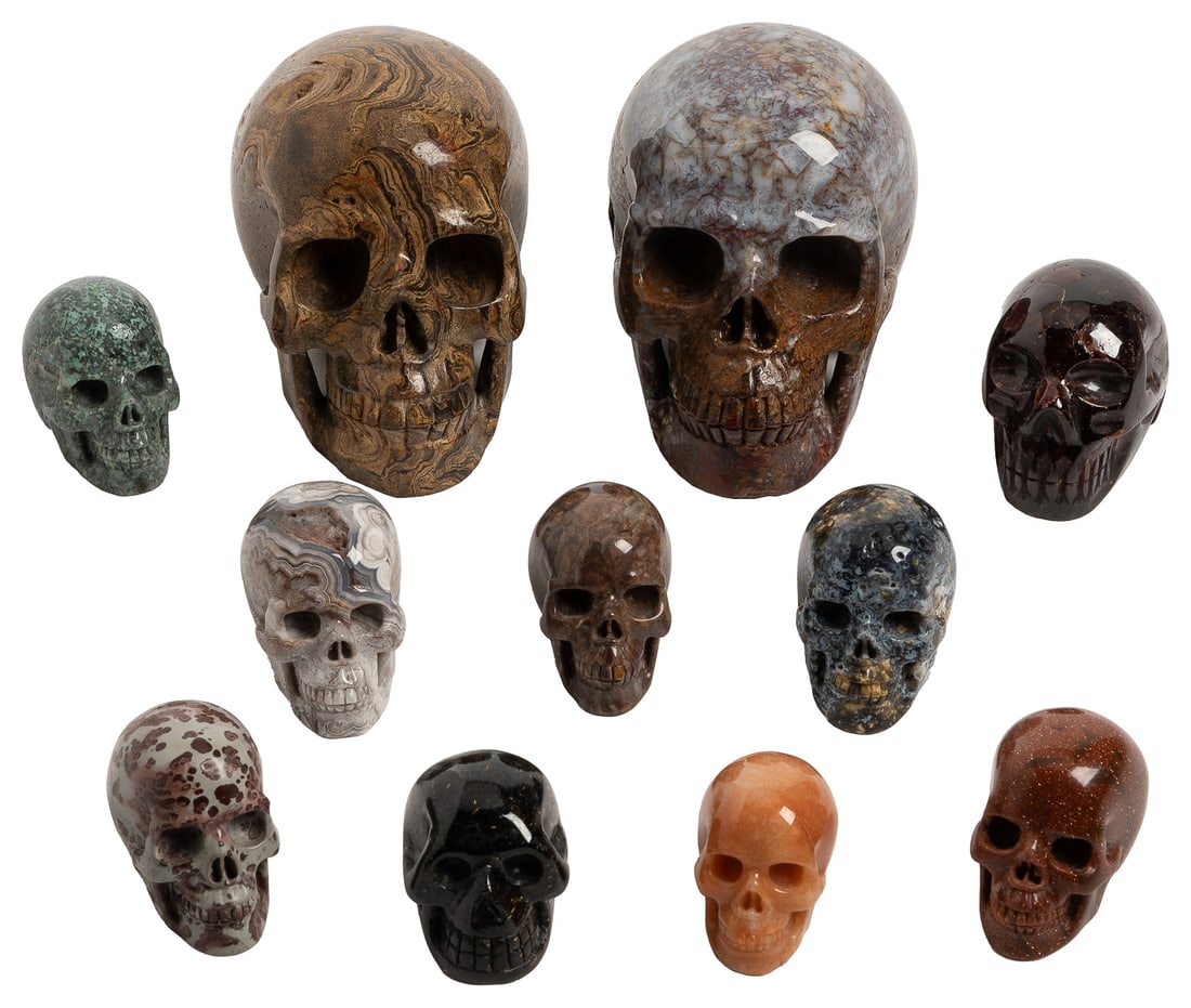 Group of Eleven Carved Semiprecious Stone Skulls. Including...: Group of Eleven Carved Semiprecious Stone Skulls. Including two large (stromatolite fossil [South Africa] and pietersite [China]) and nine smaller (star garnet, crazy lace agate [Madagascar], gold san
