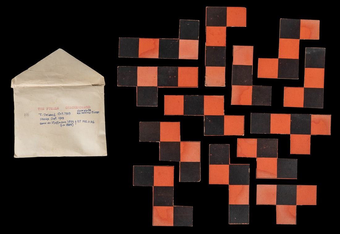 DELAND, Theodore (1873-1931). The Puzzle Checkerboard. The ...: DELAND, Theodore (1873-1931). The Puzzle Checkerboard. The Sphinx, No. 7, Sept. 1909. Red and black checkerboard puzzle on thick cardstock, 14 pieces. With text verso “it can be done, but YOU ca