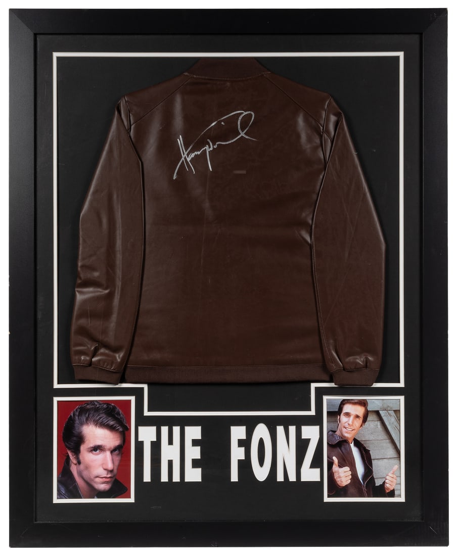 Henry Winkler signed "The Fonz" leather jacket (JSA).: Henry Winkler signed "The Fonz" leather jacket (JSA). A brown leather jacket, signed by Winkler in silver across the back, in a framed display with two photos of Winkler in his role as "Fonzie" on