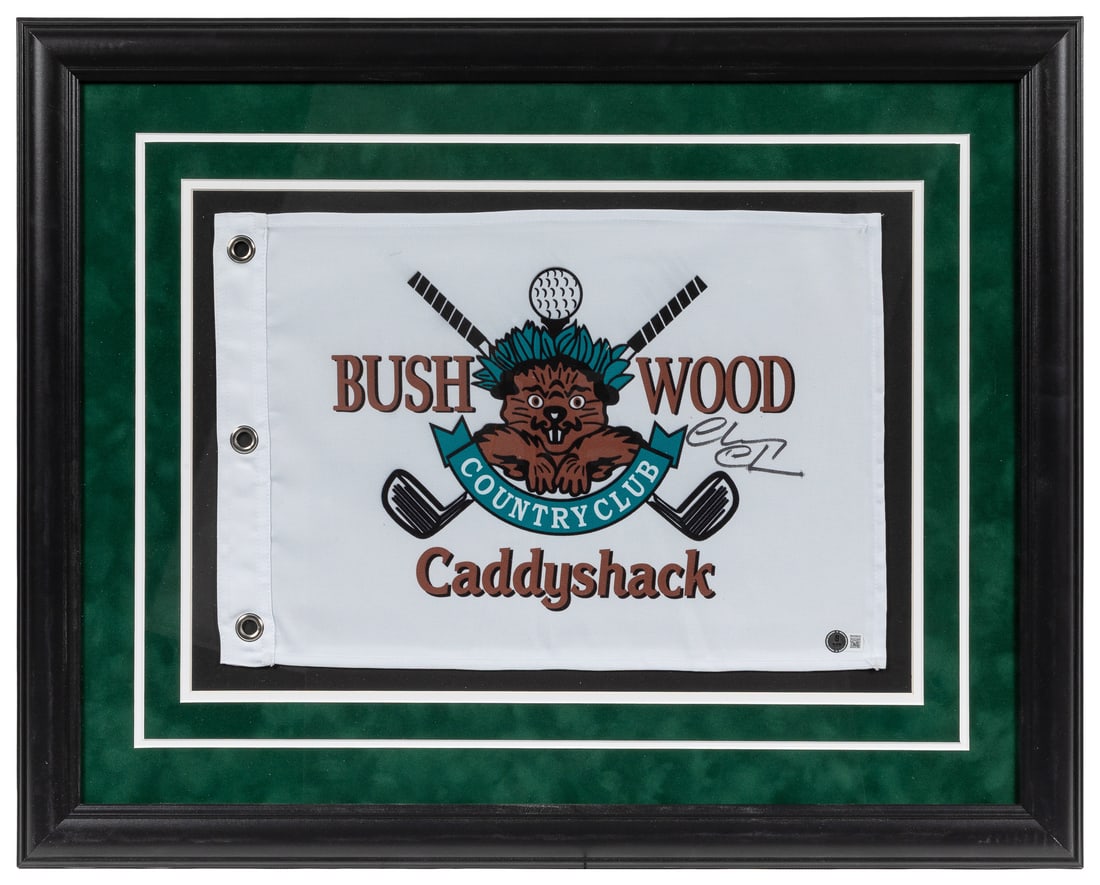 Chevy Chase Signed Caddyshack Bushwood Country Club Flag (BAS).: Chevy Chase Signed Caddyshack Bushwood Country Club Flag (BAS). Nylon flag printed in color with the Bushwood logo, signed at right by Caddyshack star Chevy Chase in black felt-tip marker.Framed and