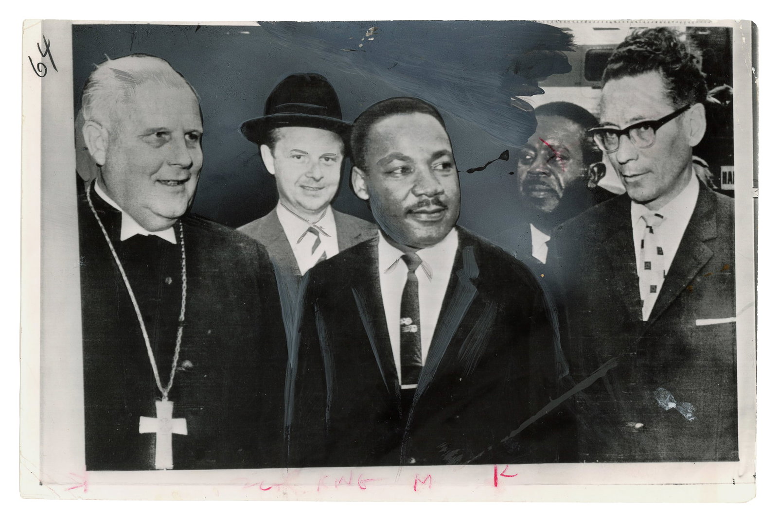 Martin Luther King Jr. in Berlin. Press Photograph. 1964.: Martin Luther King Jr. in Berlin. Press Photograph. 1964. Gelatin silver photograph depicting Dr. Martin Luther King Jr. during his visit to Berlin, shown with clergy and associates. Verso with newspa