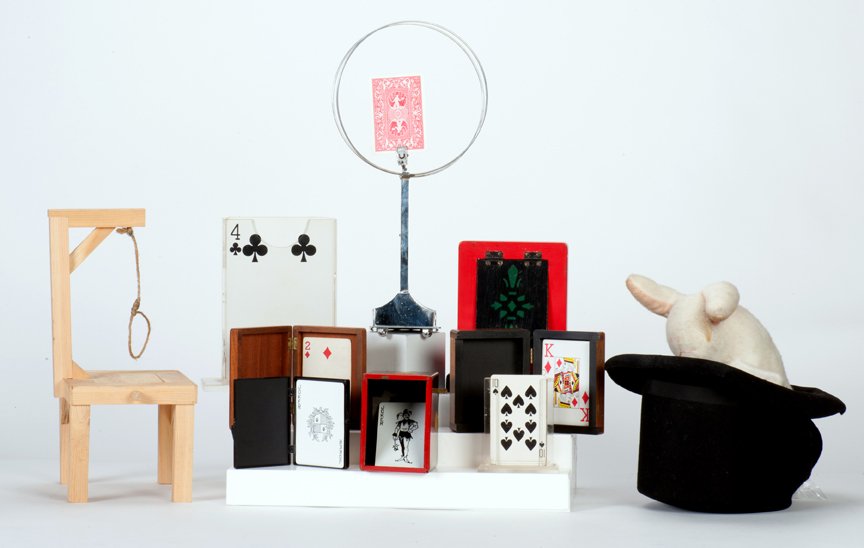 Group of ten vintage card magic props: [Card Magic] Group of ten vintage card magic props. Including Out of My Hat (Charles), Card Gallows, Card in Balloon, various wooden and plastic card boxes (including Berg’s Mento Box), a jumbo mech