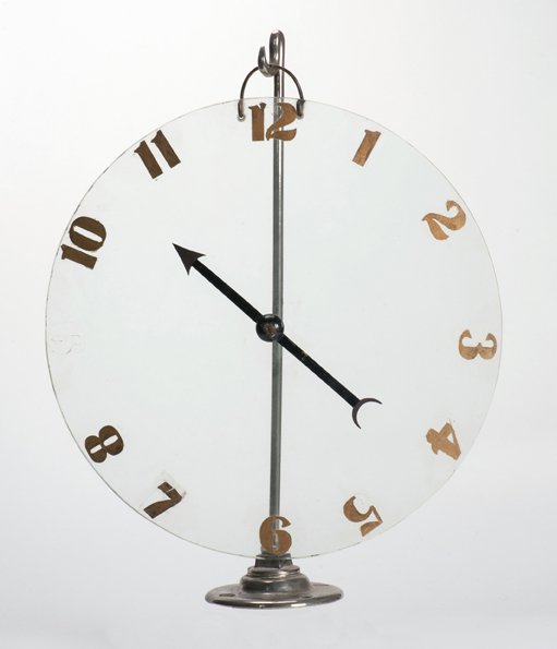 Spirit Clock. American, ca. 1915: Spirit Clock. American, ca. 1915. A clock with a glass dial is fitted with a metal pointer. A time is named and the pointer is spun. It stops on the selected hour. Glass dial 16” in diameter, stand 