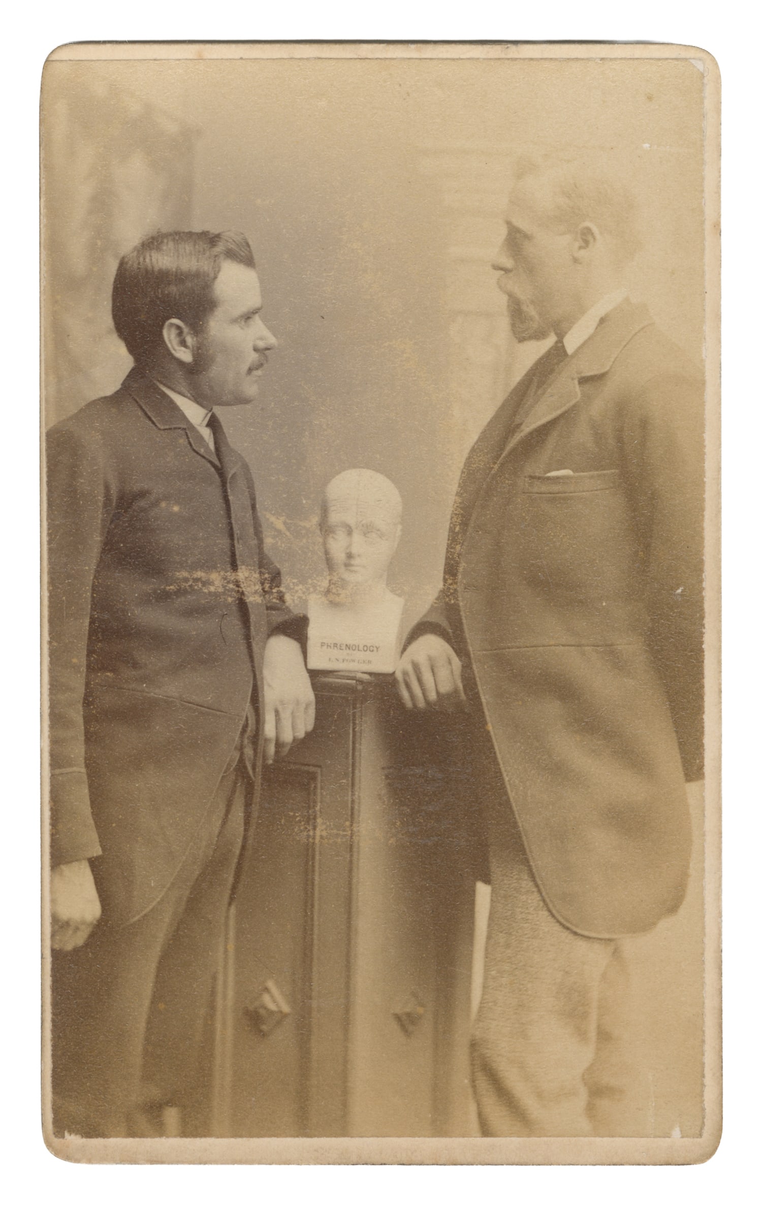[PHRENOLOGY]. CDV of Two Men with a Phrenology Bust. South Shields, UK: G. Middleton, ca. 19th: [PHRENOLOGY]. CDV of Two Men with a Phrenology Bust. South Shields, UK: G. Middleton, ca. 19th century. Sepia-toned photograph on studio mount. The men are potentially Victorian scientists. 4 x 2