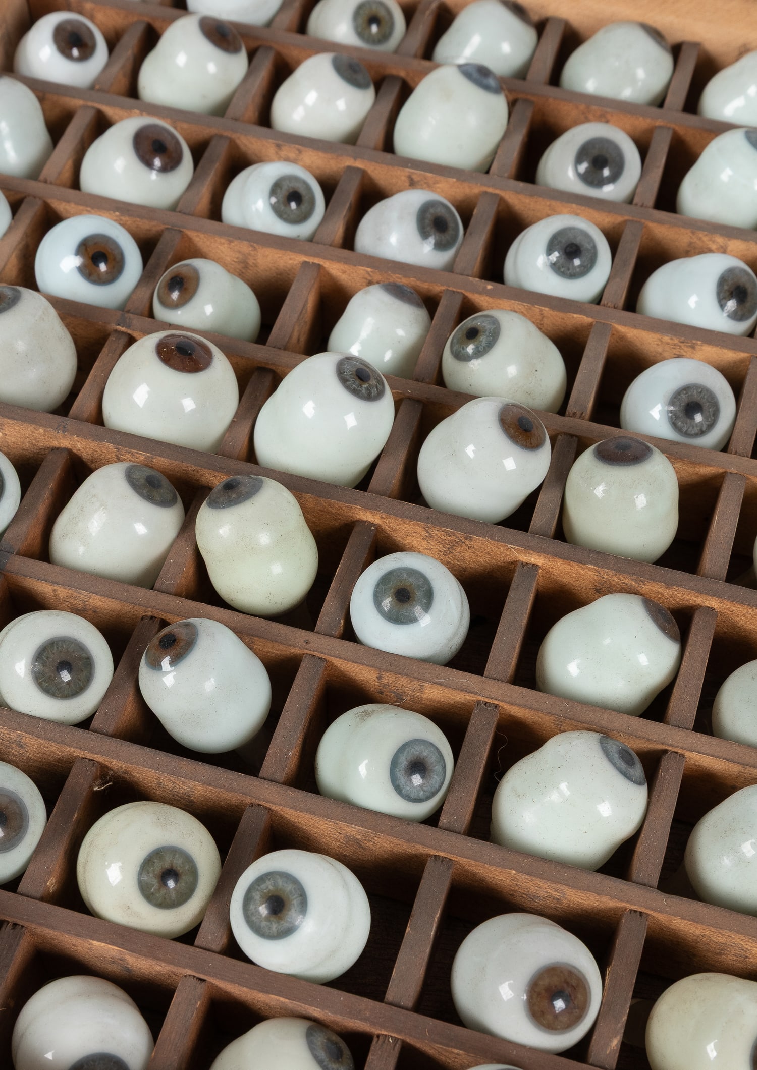 Prosthetic Glass Eye Collection. Group of 74 Brown and Blue Glass Eyes in a Wooden Grid Drawer.: Prosthetic Glass Eye Collection. Group of 74 Brown and Blue Glass Eyes in a Wooden Grid Drawer. German. Early 20th Century. Drawer 13 x 26 ¼”. Eyes approx. 1 1/2 x 1" each. Blown glass,