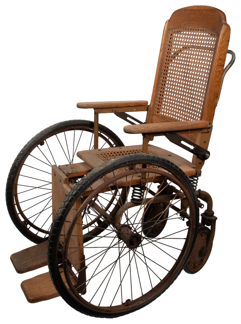 Cane Wheelchair.: Cane Wheelchair. Circa early 20th century. Metal and wood, with a wicker seat and back, and solid rubber tires. In working order with brake lever and adjustable leg rests. Height approximately: 43". C