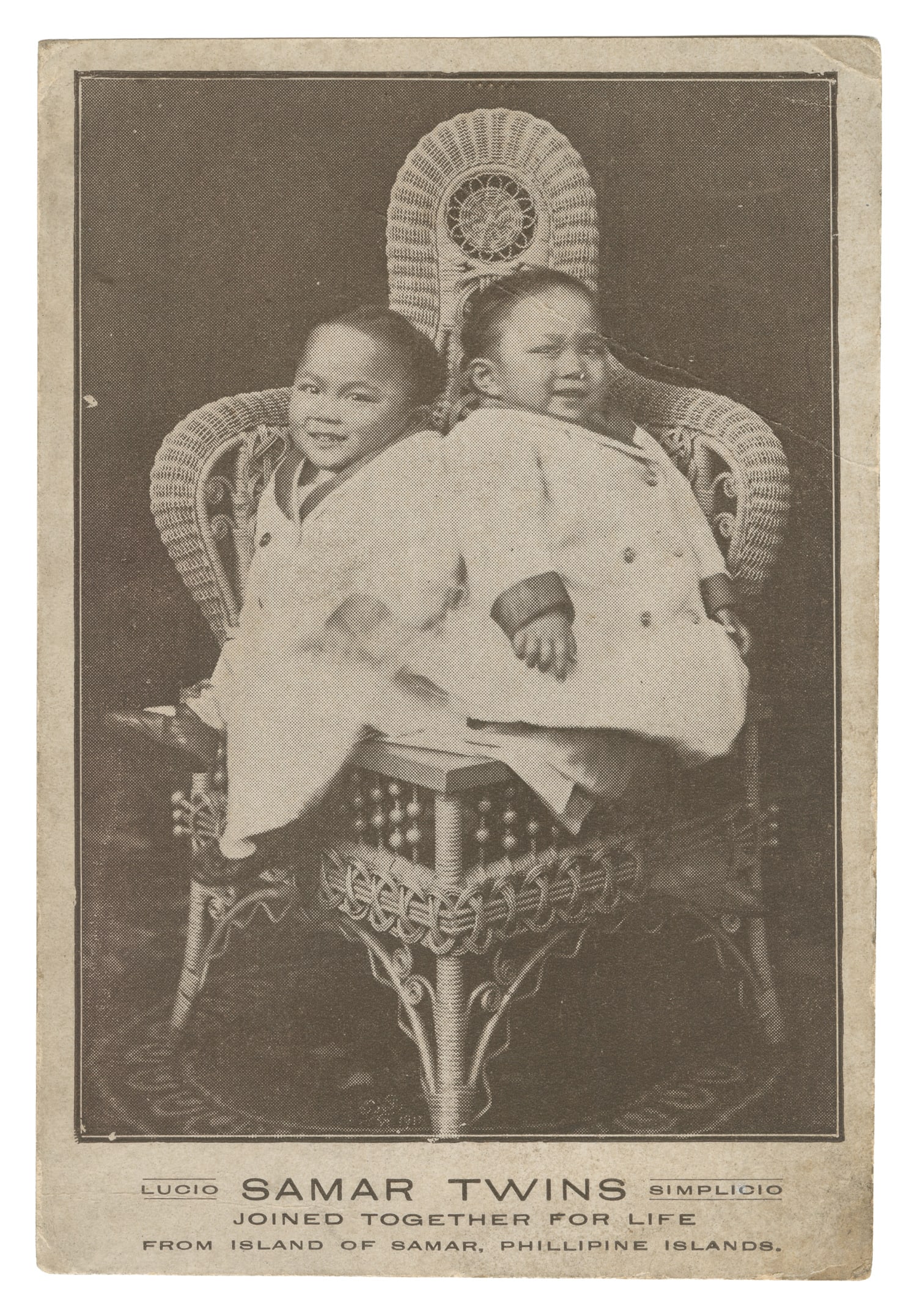 GODINO, Simplicio and Lucio (1908-1936). Souvenir Postcard of the Siamese Twins. Early 20th century.: GODINO, Simplicio and Lucio (1908-1936). Souvenir Postcard of the Siamese Twins. Early 20th century. Photograph of the twins as children sitting on a wicker chair. Billed as the Samar Twins "joined