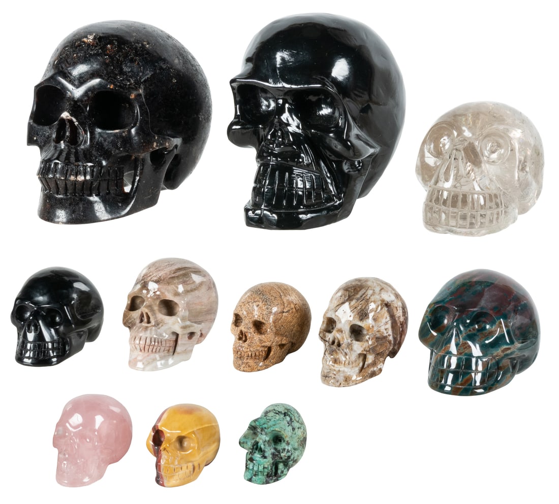 Group of 11 Carved Semiprecious Stone Skulls.: Group of 11 Carved Semiprecious Stone Skulls. Including 2 large (nuumite and obsidian) and 9 smaller (light smokey quartz, bloodstone jasper, petrified wood, black obsidian, mookaite, gold leaf