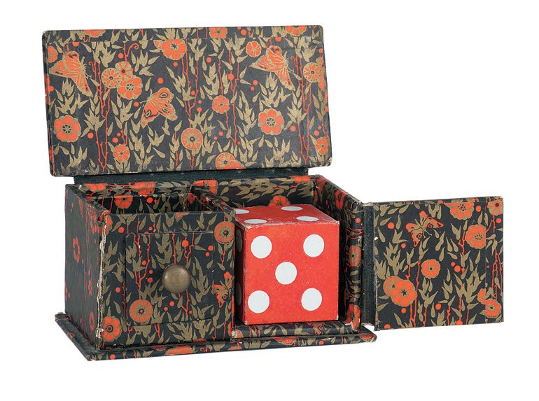 65. Die Box. New Haven, Petrie & Lewis, ca. 1930.: 65. Die Box. New Haven, Petrie & Lewis, ca. 1930. Miniature die box made of heavy paper board covered with a floral pattern. Includes 1 ¾” paper-covered wooden die, shell, and box. Hinges, bottom, 