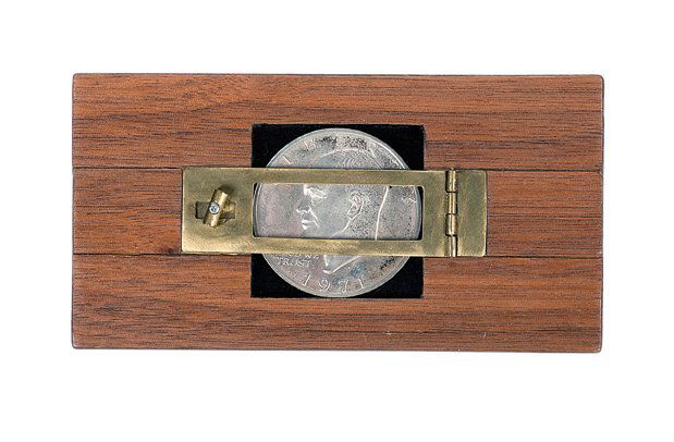 254. Zig-Zag Dollar. California, Mark Teufel, ca. 2000.: 254. Zig-Zag Dollar. California, Mark Teufel, ca. 2000. An Eisenhower Silver Dollar is placed into a wooden frame with brass hardware, is visibly split into three pieces, and then restored. Frame 4 ¾