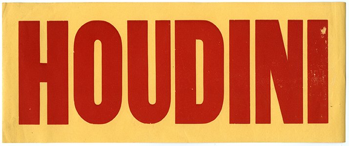 Houdini, Harry. Houdini luggage label. Circa 1920.: Houdini, Harry. Houdini luggage label. Circa 1920. Bold red block capitals spelling out “HOUDINI” printed on a pale orange sheet, reverse gummed for use on trunks and luggage. 11 x 4 ½”.