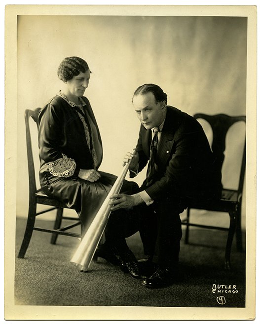 Two photos of Houdini and a spirit medium.: Houdini, Harry. Two photographs of Houdini and a “spirit medium.” Chicago, Butler Studio, ca. 1924. Houdini listens to ethereal voices projected through a spirit trumpet, and holds the trumpet in 