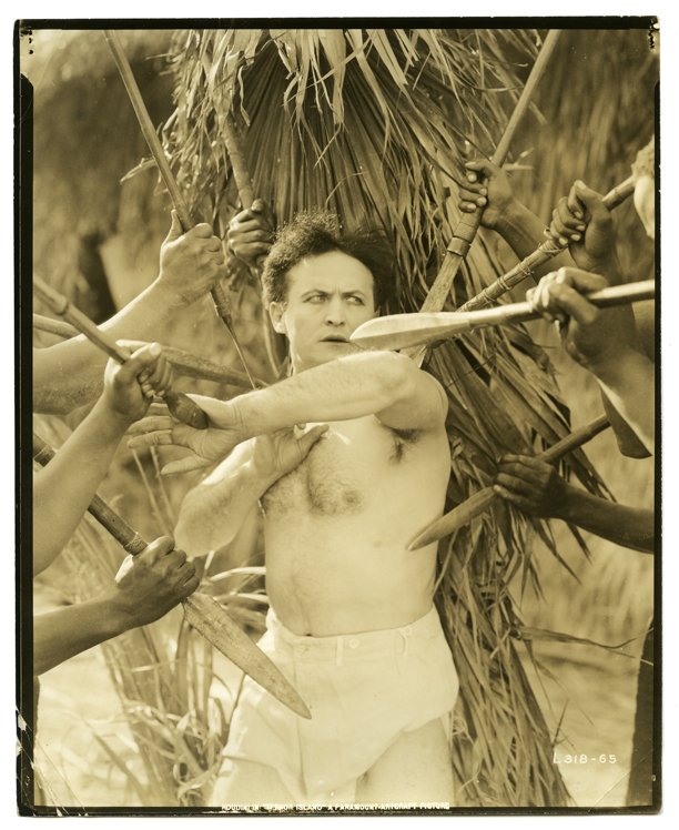 Houdini, Harry. Houdini Terror Island Film Still. 1920.: Houdini, Harry. Houdini Terror Island Film Still. 1920. Houdini, stripped to the waist, glares at nine sharp spears being thrust at him. 8 x 10”. Lower left creased and chipped.