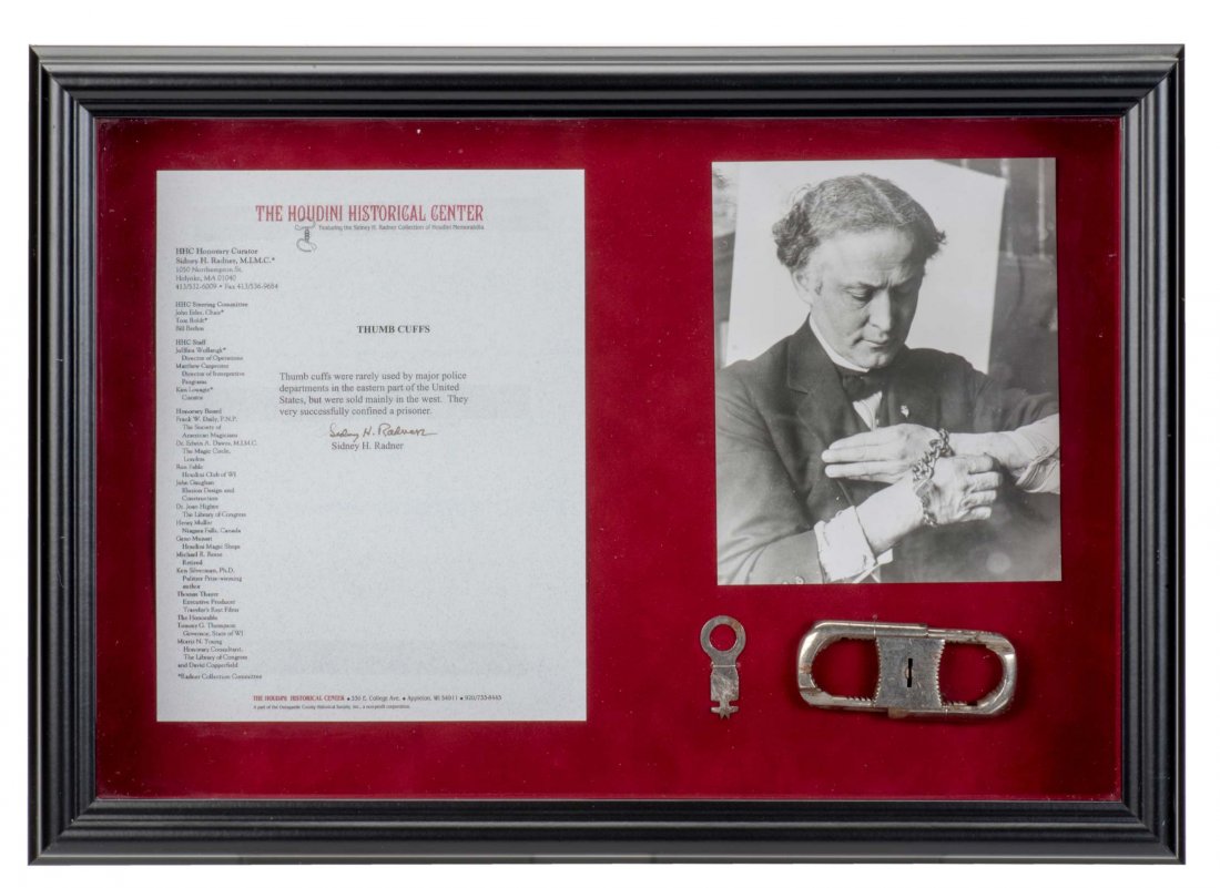 Houdini Thumb Cuffs in Shadowbox. Early twentieth: Houdini Thumb Cuffs in Shadowbox. Early twentieth century. Small metal thumb cuffs, with key, displayed in a felt-lined shadowbox also containing a letter by Sidney Radner on Houdini Historical Center