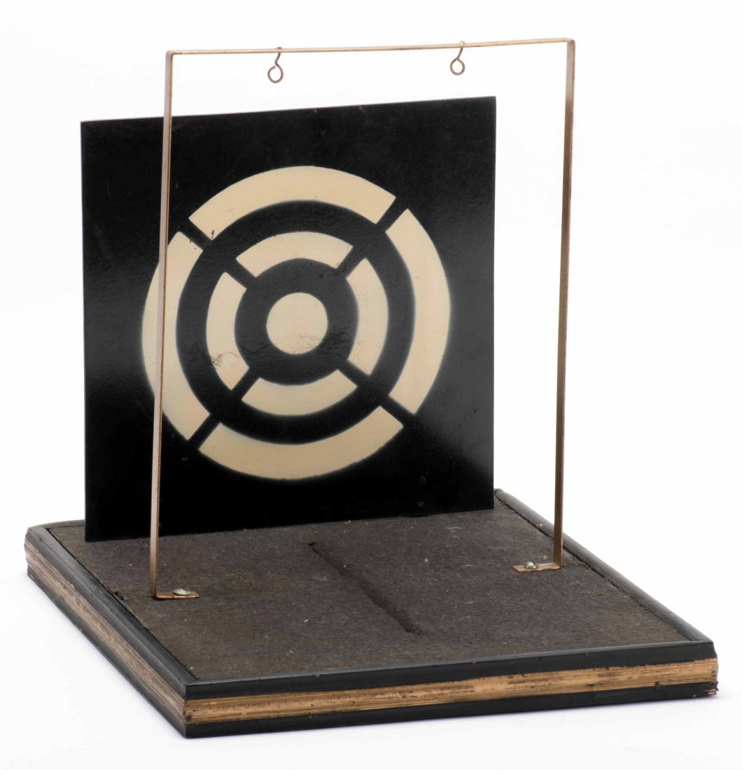 Bullet Proof Girl. Colon: Abbotts Magic Novelty Co.,: Bullet Proof Girl. Colon: Abbotts Magic Novelty Co., ca. 1959. A pane of glass hangs on a stand in front of a target and a girl stands in front of both. The magician shoots a rifle at the target, shat