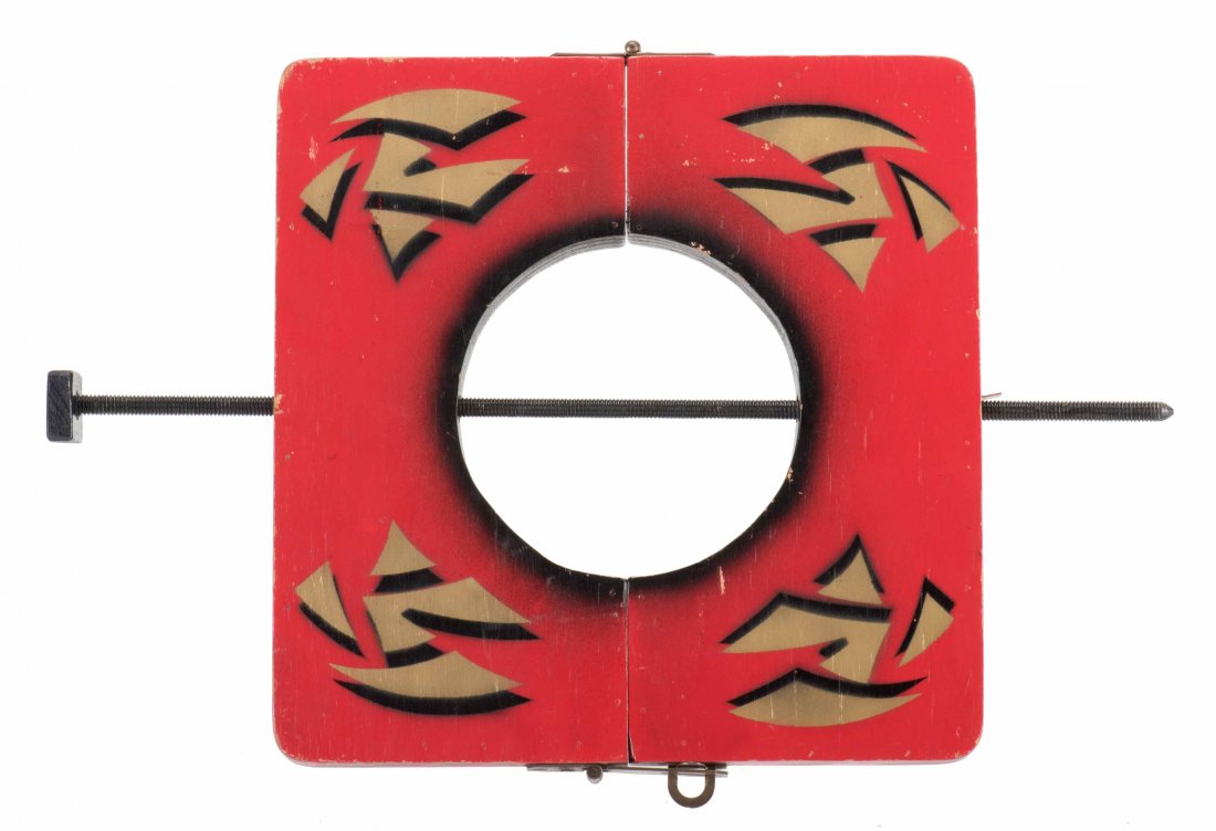 Spike Thru Neck. Colon, Mich.: Abbotts, ca. 1940s.: Spike Thru Neck. Colon, Mich.: Abbotts, ca. 1940s. Wooden stencil-painted hinged frame with brass hasp and handles, and three long spikes, one of which is visibly driven through the neck of an assista