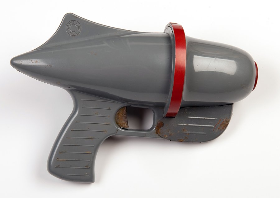 Smoke Ring Toy Gun. Beverly Hills, Calif.: Nu-Age: Smoke Ring Toy Gun. Beverly Hills, Calif.: Nu-Age Productions Inc., ca. 1950s. Gray plastic and metal smoke ring toy gun. 9 _ x 6. Some scuffs and oxidation affecting most of trigger and patches of ot