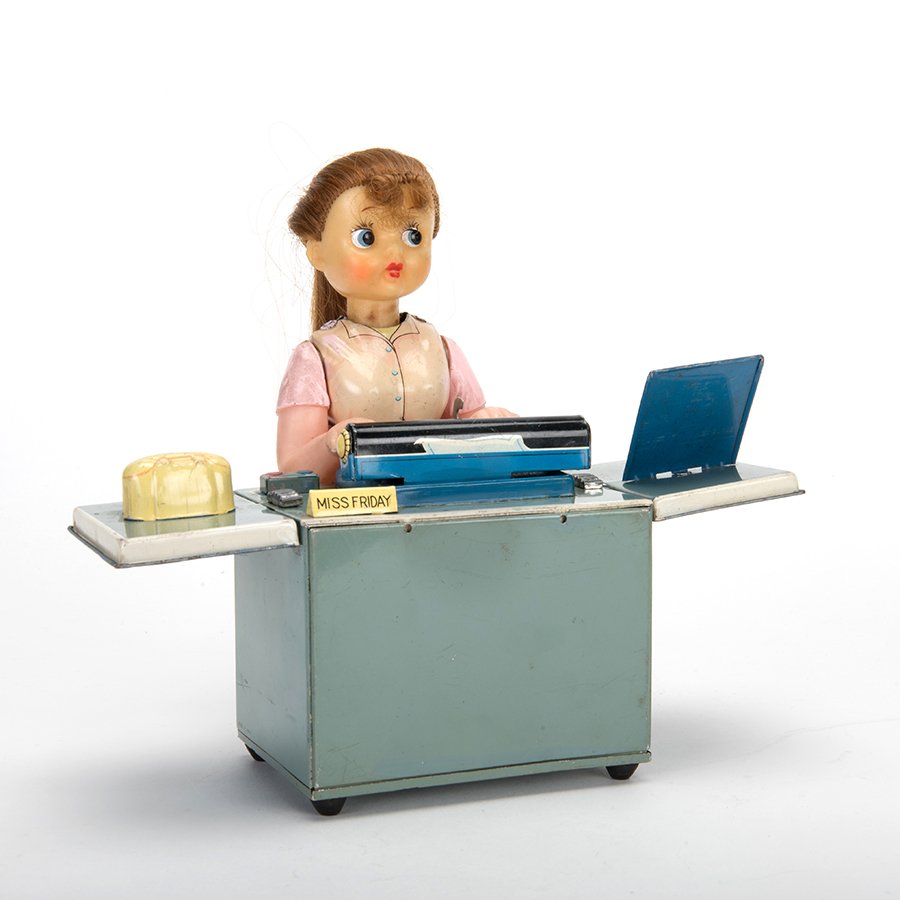 Miss Friday. Japan, mid-twentieth century. Battery: Miss Friday. Japan, mid-twentieth century. Battery operated tin litho toy with some plastic components. Miss Friday works on her typewriter and has a fold out desk. 4 _ x 5 x 8. Some hairs askew, soil
