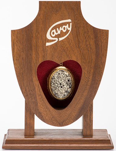The Savoy. Huntington Beach: Magikraft Studios, 1993. A: The Savoy. Huntington Beach: Magikraft Studios, 1993. A wooden stand allows the magician to switch one metal locket for a duplicate in the action of pulling the first locket free. With original instru