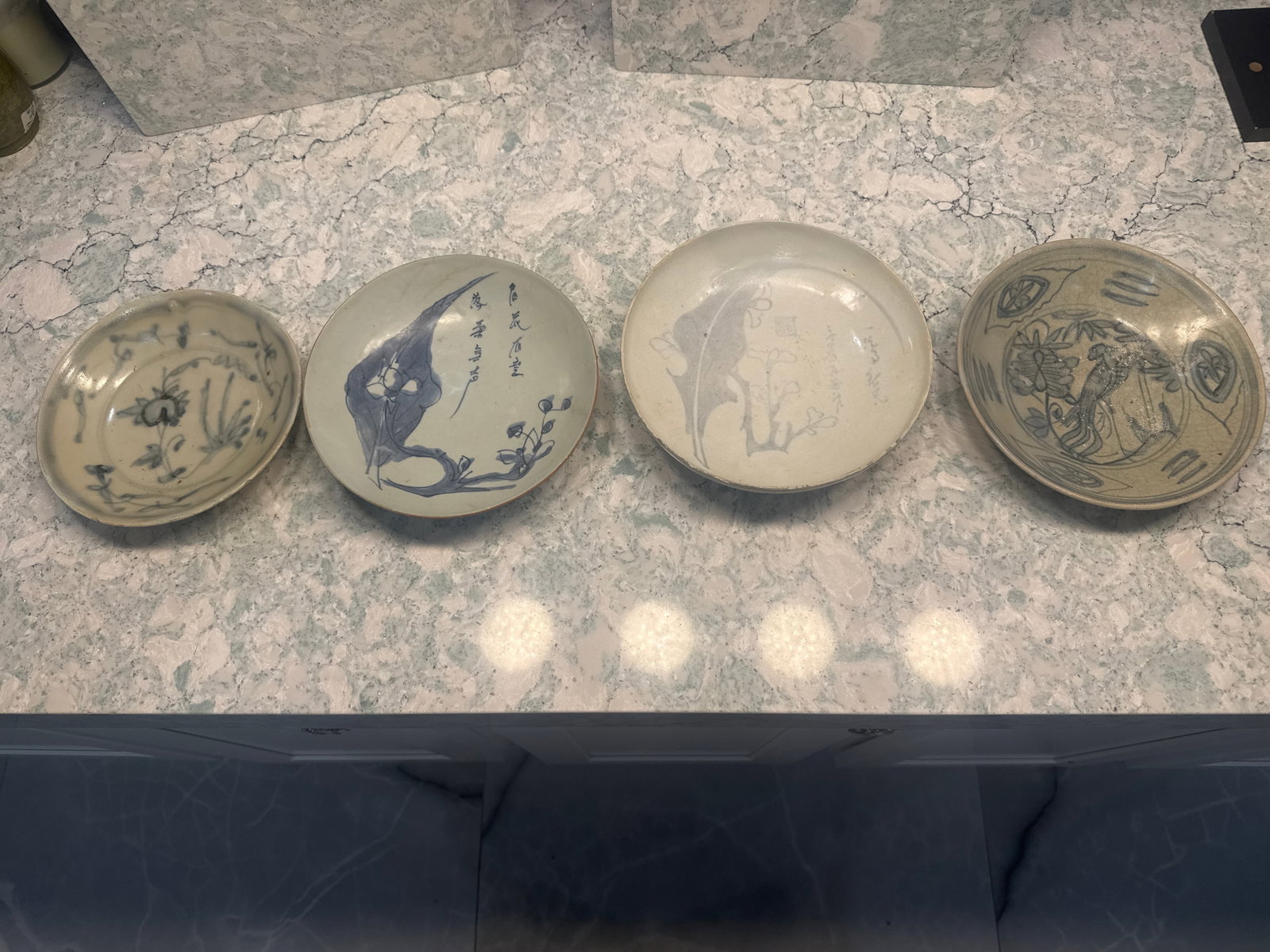Four Varied Blue-and-White Shipwreck Bowls with Calligraphic and Figurative Decoration - Varied Size: An assorted group of four underglaze blue porcelain bowls recovered from a likely Southeast Asian shipwreck. Each bowl is distinct in style and production origin:- Bowl 1 (Tag: VFO 5678): Light gray g