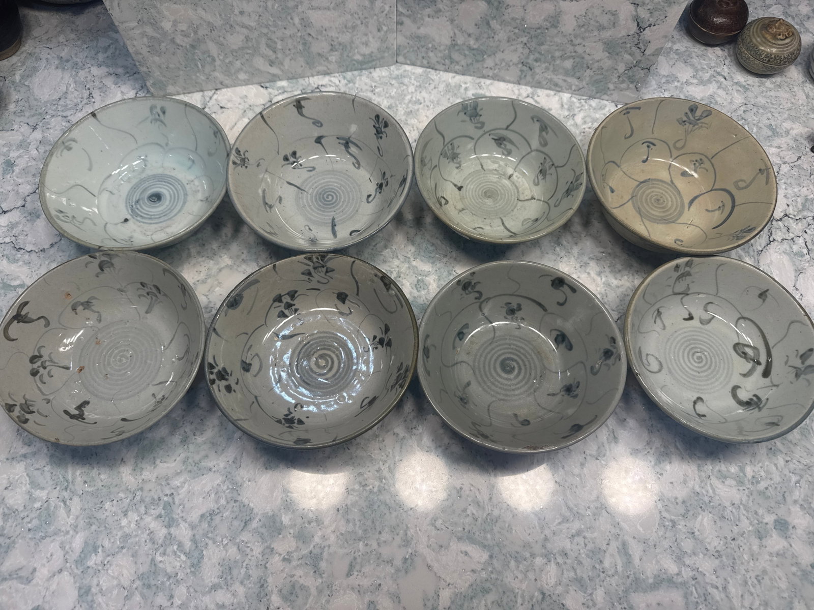 Group of Eight Painted Vietnamese Shipwreck Bowls with Spiral Centers 6" x 2.5": "A well-matched group of eight Vietnamese stoneware bowls decorated in underglaze iron-black slip with scrolling floral and vine motifs. Each bowl features a classic spiral-turned base in the interior