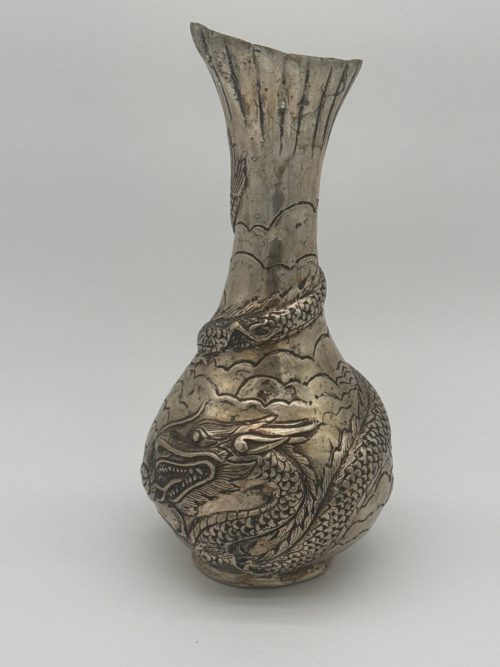 Hand-Chased Metal 12-inch Dragon Vase with Cloud Motif: This 12-inch tall hand-chased metal vase features an elaborate three-dimensional relief of a coiling Asian dragon encircling the body and neck, with stylized clouds and waves forming the background. T