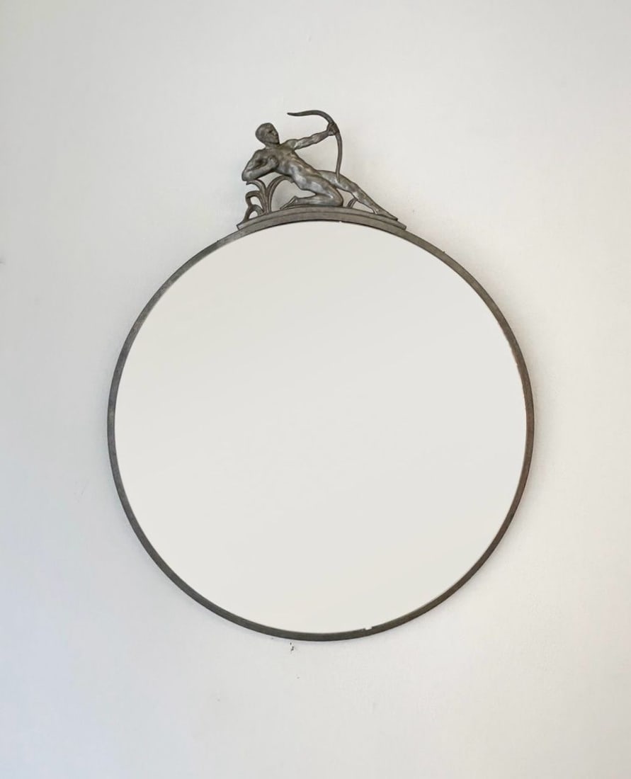 CG Hallberg, attribué à .Modèle 5412.: CG Hallberg, attribué à .Modèle 5412.Miroir mural circulaire avec en haut, un motif représentant un homme nu avec un arc.Etain, et miroir .Date de création : « Swedish Grace », vers 1930.H59 L4