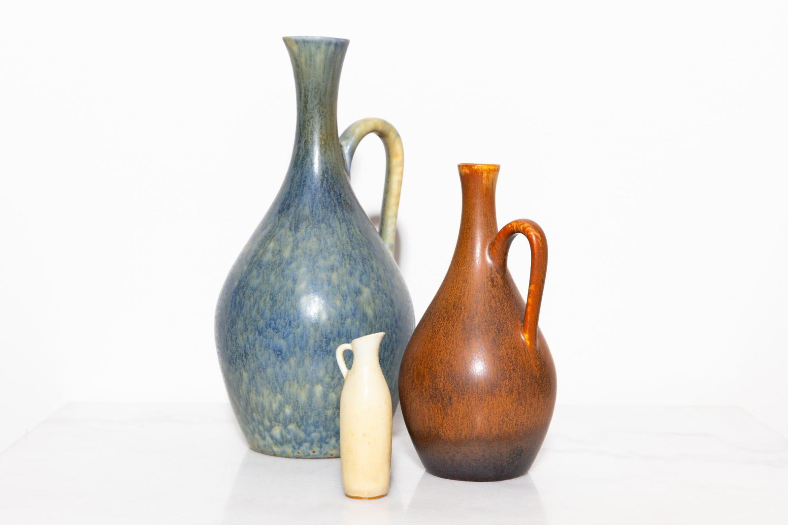 Carl-Harry Stålhane.Vases à anse (Modèle SYR).Grès émaillé.Signé Rörstrand.H23 cm.H16 cm.H8: Carl-Harry Stålhane.Vases à anse (Modèle SYR).Grès émaillé.Signé Rörstrand.H23 cm.H16 cm.H8 cm..Trois vases à anse modèle SYR en grès émaillé. Signés Rörstrand. H 23 cm, H 16 cm, H 8 cm