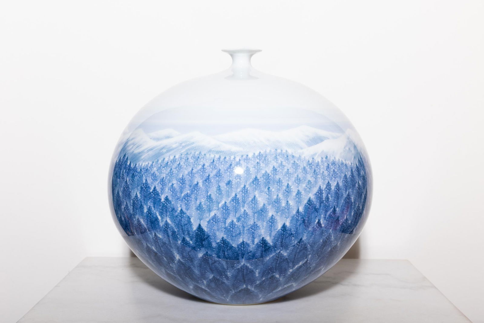 Fujii Shumei (né en 1936).Monts d'Arita enneigés.Vase large à petit col trilobé.Porcelaine bleu: Fujii Shumei (né en 1936).Monts d'Arita enneigés.Vase large à petit col trilobé.Porcelaine bleu et blanc, motifs en empreinte de feuilles et nervures.Signé.Date de création : vers 1980.H 29 ? 31