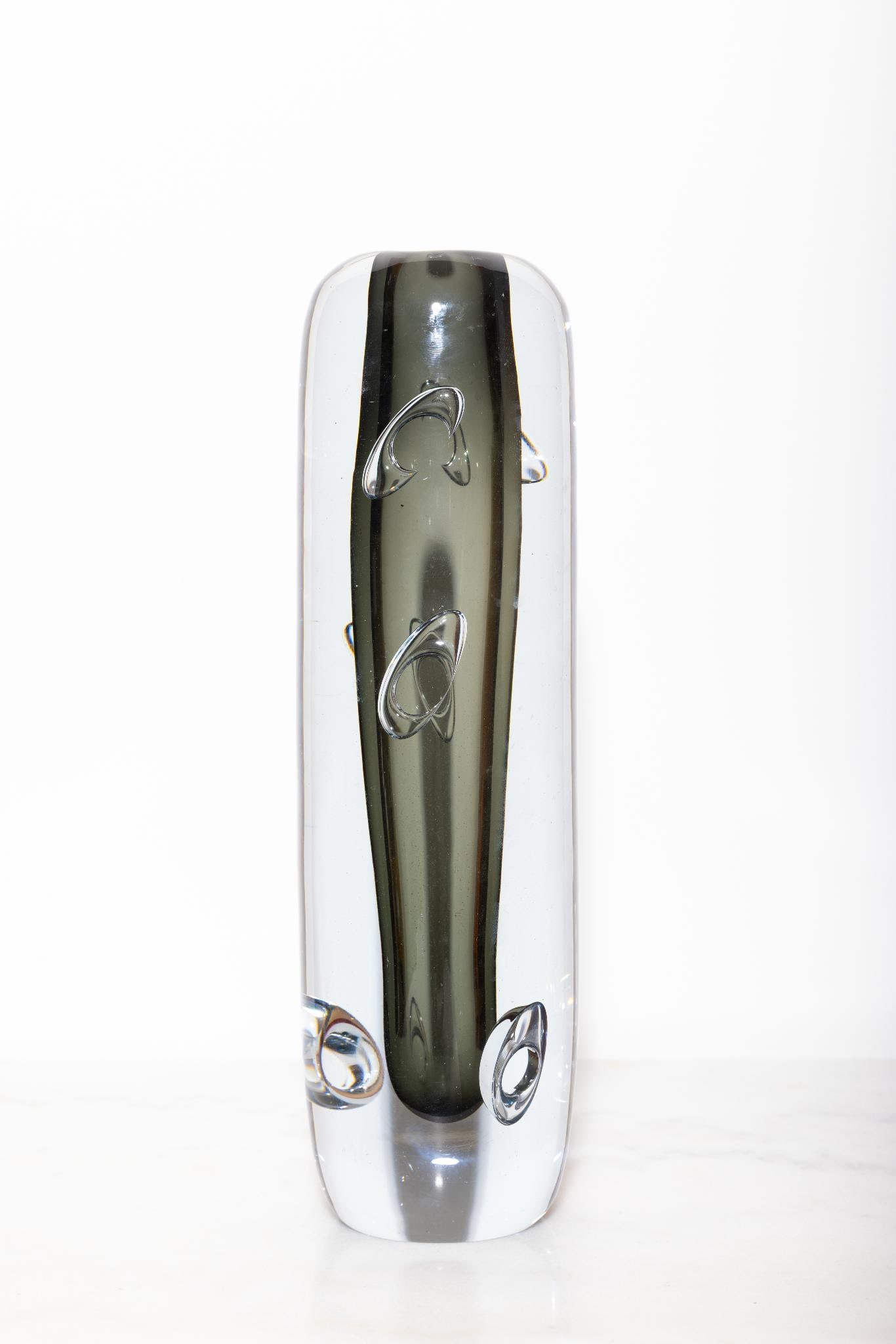 Asta Strömberg.Vase en verre Strömbergshyttan avec des bulles d'air en forme d'anneaux.Verre: Asta Strömberg.Vase en verre Strömbergshyttan avec des bulles d'air en forme d'anneaux.Verre transparent et verre fumé..Signé "Strömberg B 942".H27,5 cm..Vase signé — la signature « Strömber