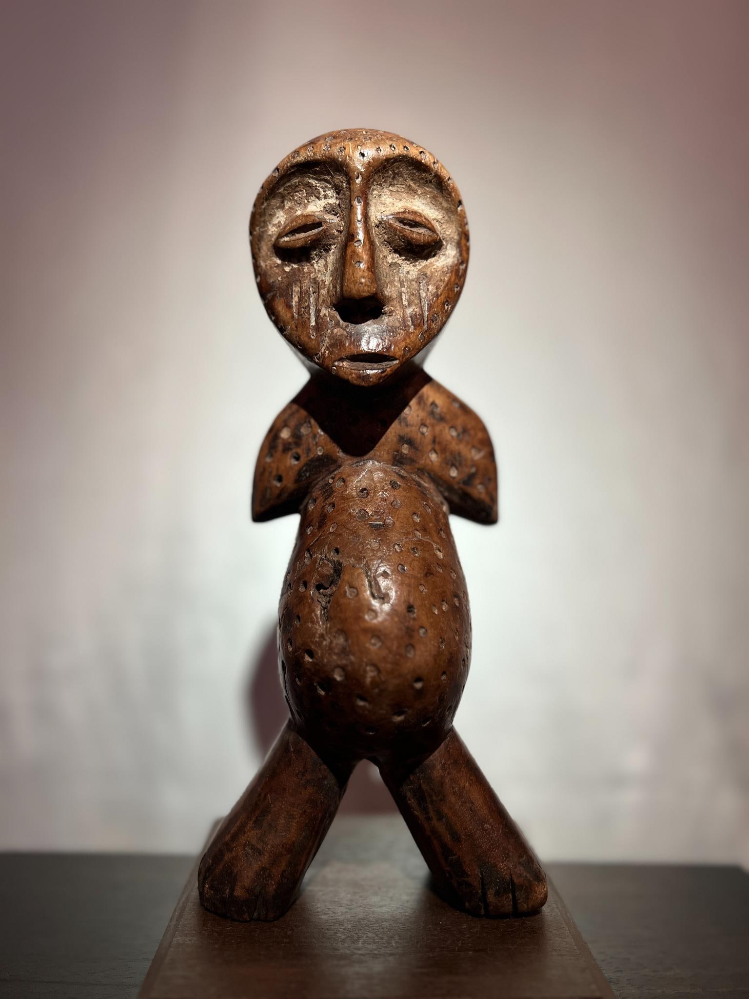 Lega Statuette, Bwami Society Sculpture Wood with a deeply lustrous honey-brown patina, accented: Lega Statuette, Bwami Society SculptureWood with a deeply lustrous honey-brown patina, accented with white mineral pigment (kaolin and mica), traces of ritual useDemocratic Republic of the Congo, mid-