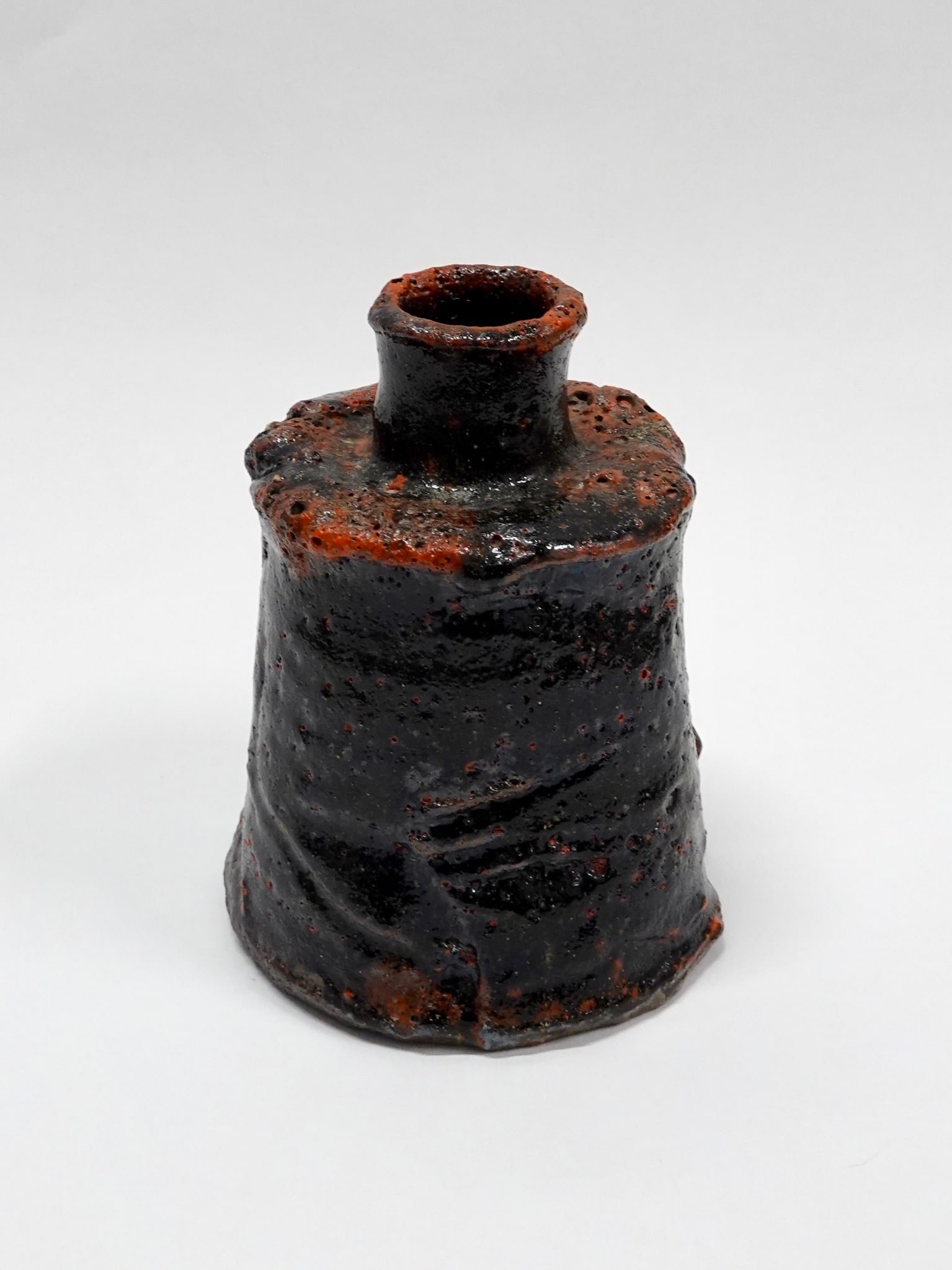 Hans Vangsø (1950) Small Red Bottle Local stoneware and glaze Denmark H17 Ø13 cm A small bottle: Hans Vangsø (1950)Small Red BottleLocal stoneware and glazeDenmarkH17 Ø13 cmA small bottle crafted from local stoneware, featuring a glaze with reddish hues. The artist fires his pieces encased in c