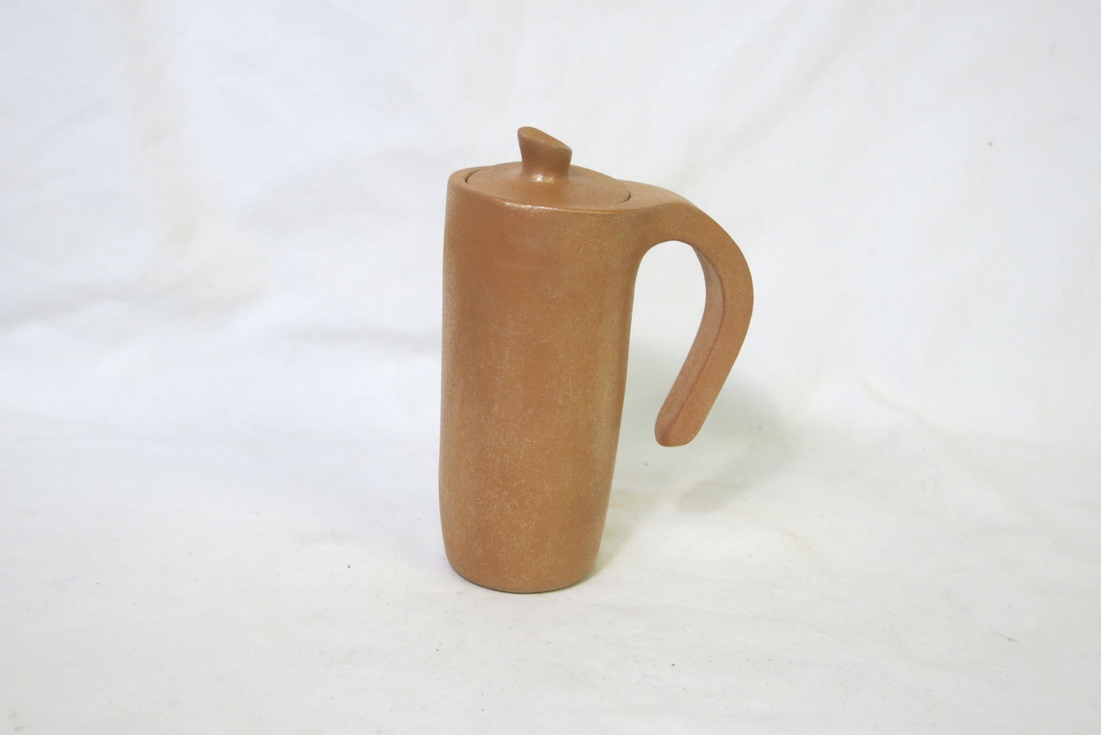 Eric Marcus Taos Pueblo Micaceous Creamer: Signed Eric Marcus on bottom. A golden micaceous creamer to go with the sugar bowl in the previous lot. The vessel is made from local clay that is naturally rich in mica, giving it a distinctive shimm