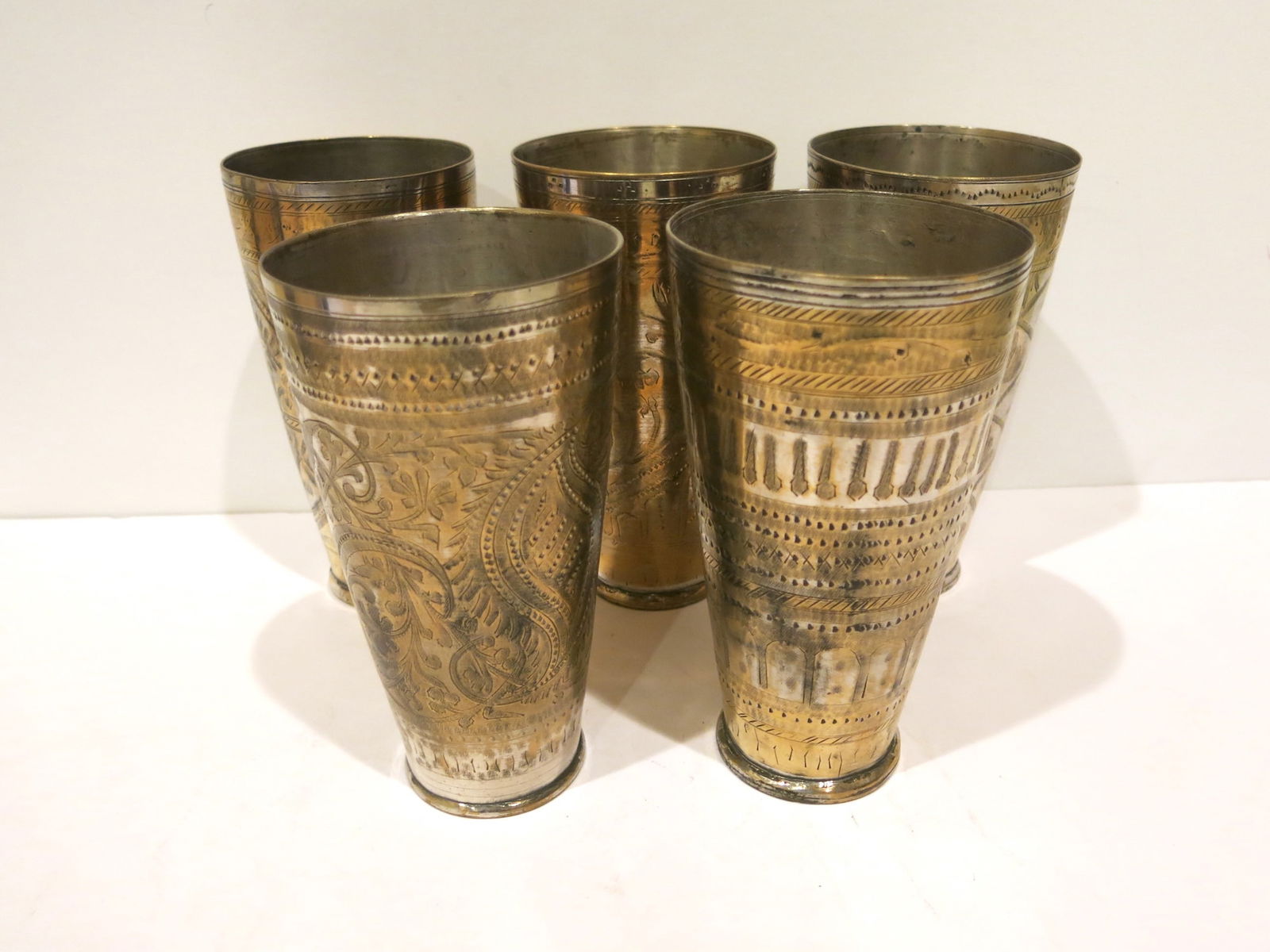 Early 20th C. Persian Silvered Bronze Engraved Beaker Set of Five: Silvered bronze beaker with heavy Persian motifs. These beakers are made from bronze or copper that has been treated with a silver wash or plating, giving them a lustrous, silvery appearance. The prim