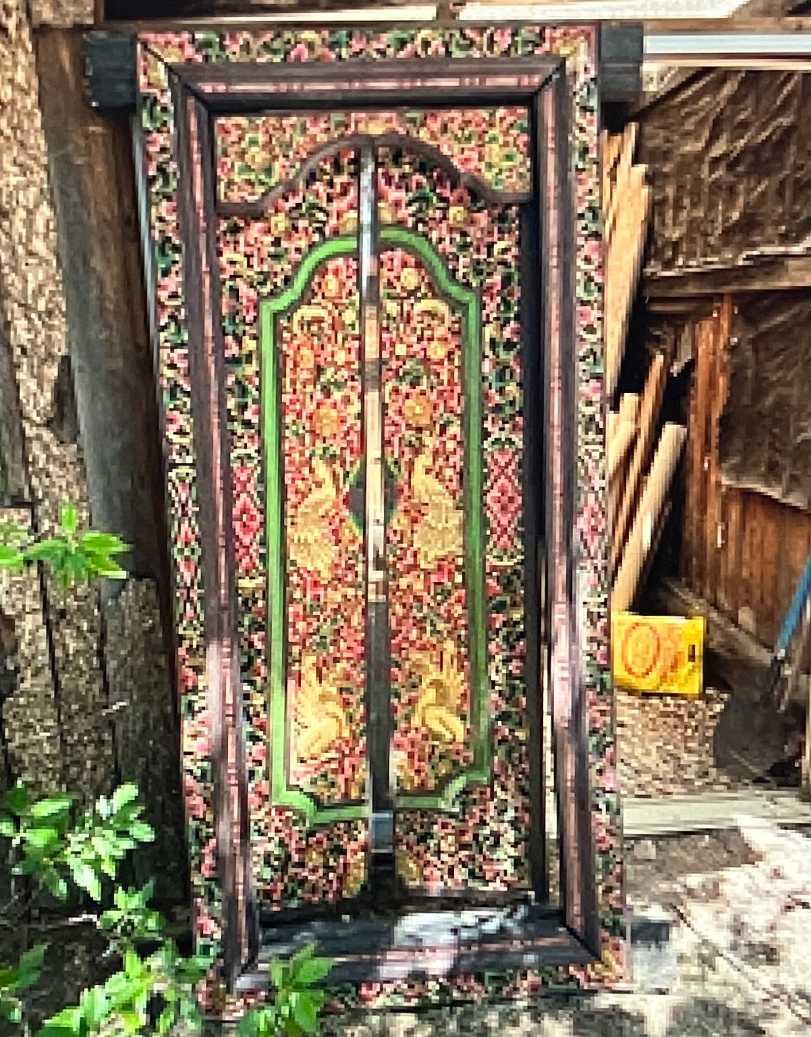 Antique Hand-Carved and Painted Balinese Door: The door features extensive, intricate hand-carved designs characteristic of Balinese folk art. Common motifs include stylized flowers, birds (like the gold figures in the central panels), and geometr
