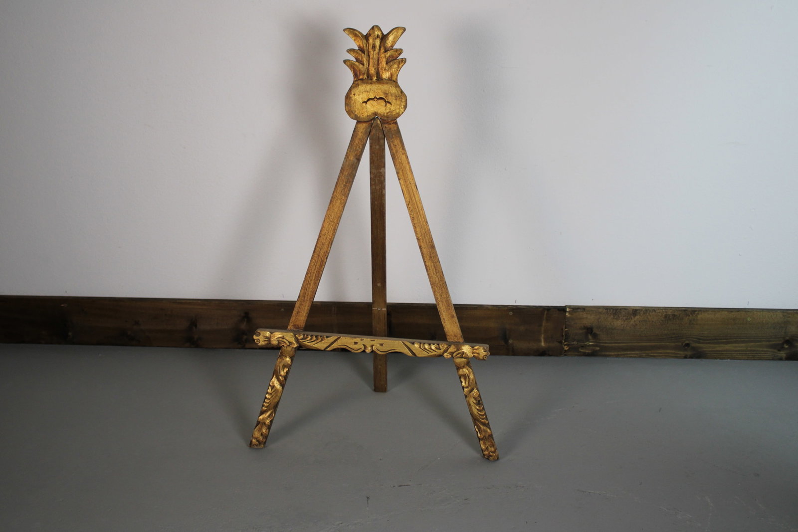 Italian Style Gilded Carved Wood Art Display Easel 37"x21.5": A small-scale gilt-wood display easel with a pierced foliate crest terminating in a stylized pineapple finial. The tripod legs cross at the crest and splay to a carved lower stretcher flanked by griff