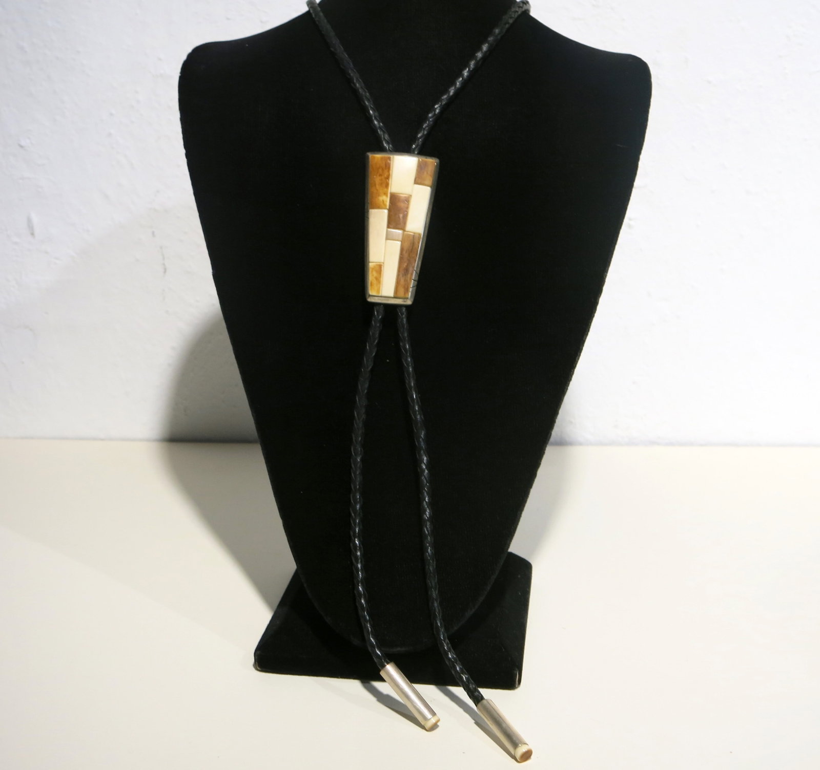 Southwestern Bone Mosaic Silver Bolo Tie: A Southwestern-style bolo tie with a tapered rectangular silver-framed slide set with a geometric mosaic of natural and pyrography (heat/scorch-decorated) bone tiles. The slide is bezel-set in a silve