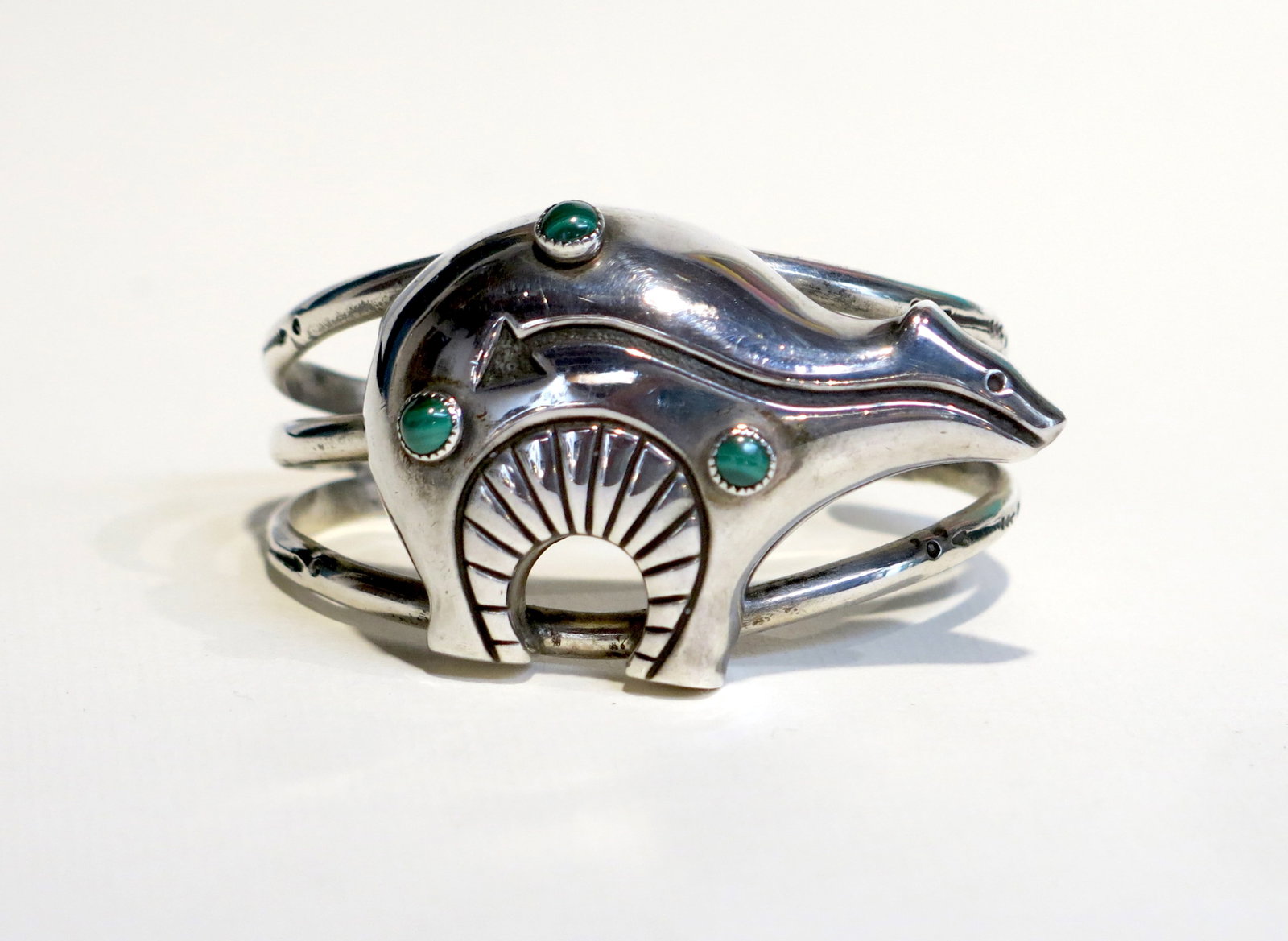 Navajo Sterling Bear Cuff Bracelet Malachite: The bear figure is fully rendered in high-relief repoussé: a smooth domed body with a sinuous flowing back line, a distinct head with a pointed snout, four legs, and a prominent chest cavity featurin