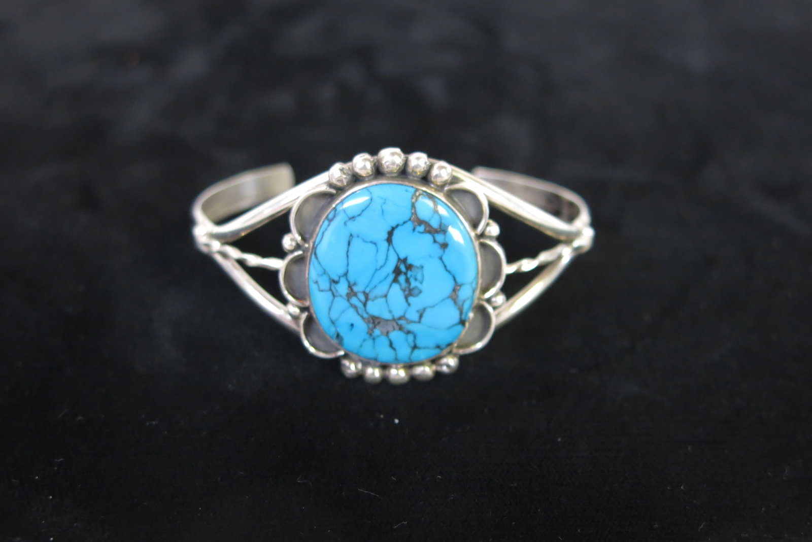 Navajo Sterling Kingman Turquoise Twist Cuff: A Navajo (Diné)-made sterling silver cuff bracelet with a split, twisted-wire double shank rising to a scalloped, shell-lobed silver mounting that holds a single large round turquoise cabochon. The c