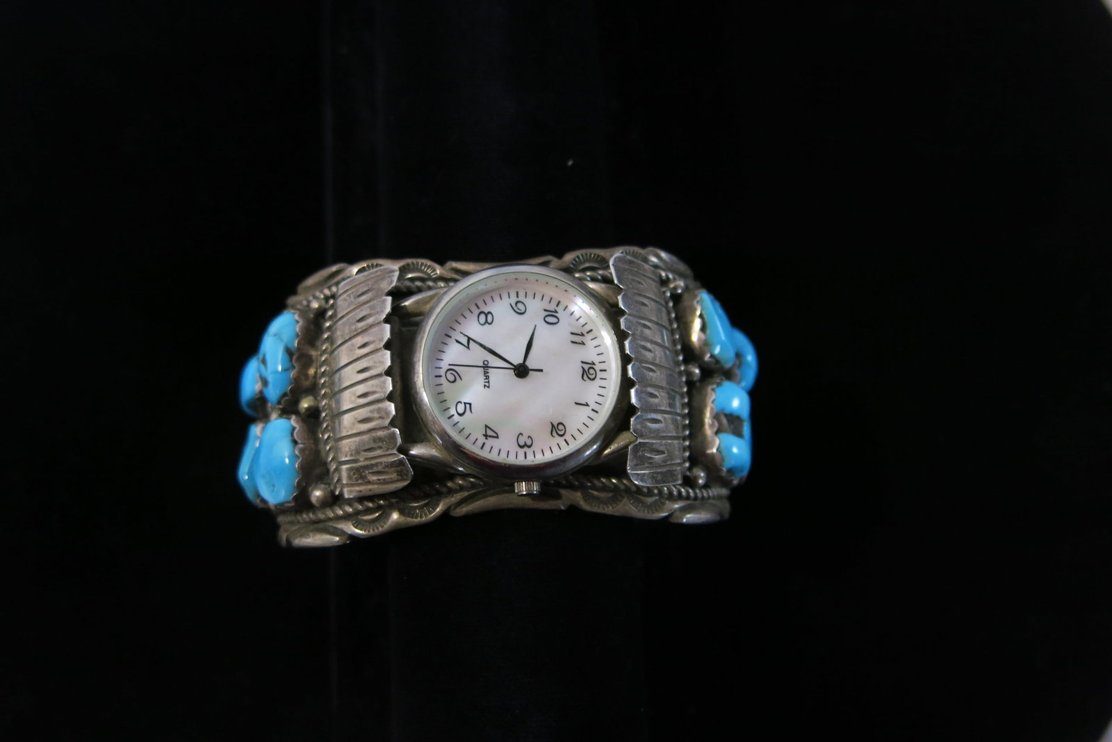 Old Pawn Navajo Sleeping Beauty Watch Cuff: A Navajo (Diné)-made sterling silver watch cuff bracelet, with a functioning quartz wristwatch (white dial, black hands and numerals) set into fluted, coin-edge silver shoulder panels with chased edg