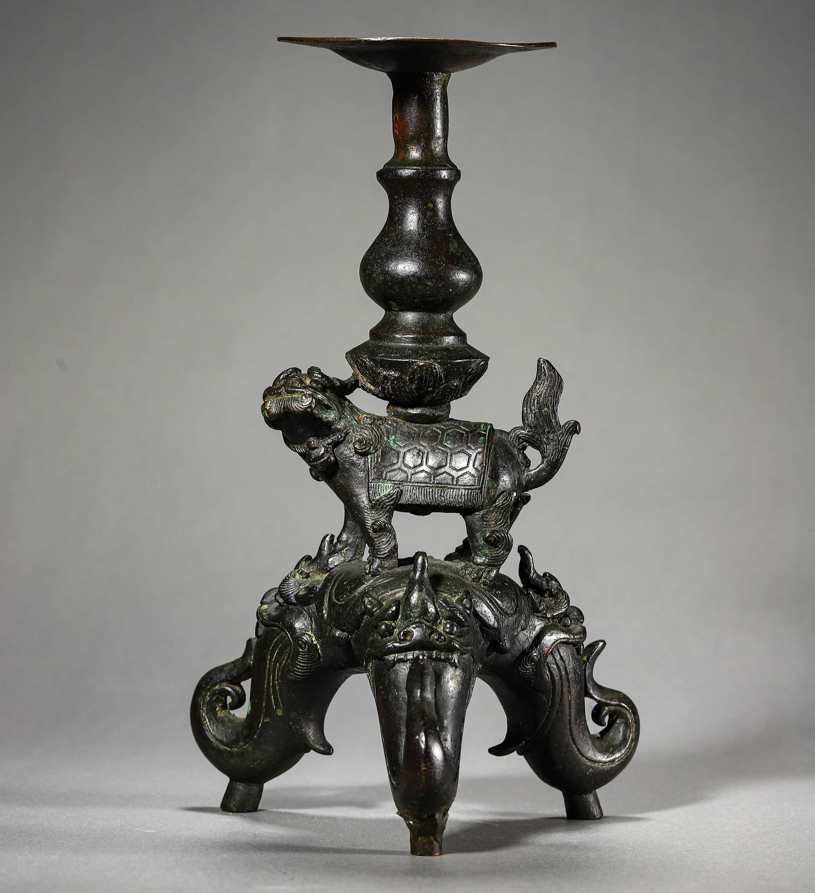 A CHINESE BRONZE CANDLESTICK WITH THREE-ELEPHANT LEGS AND LION DECORATIONS (1 of 3)