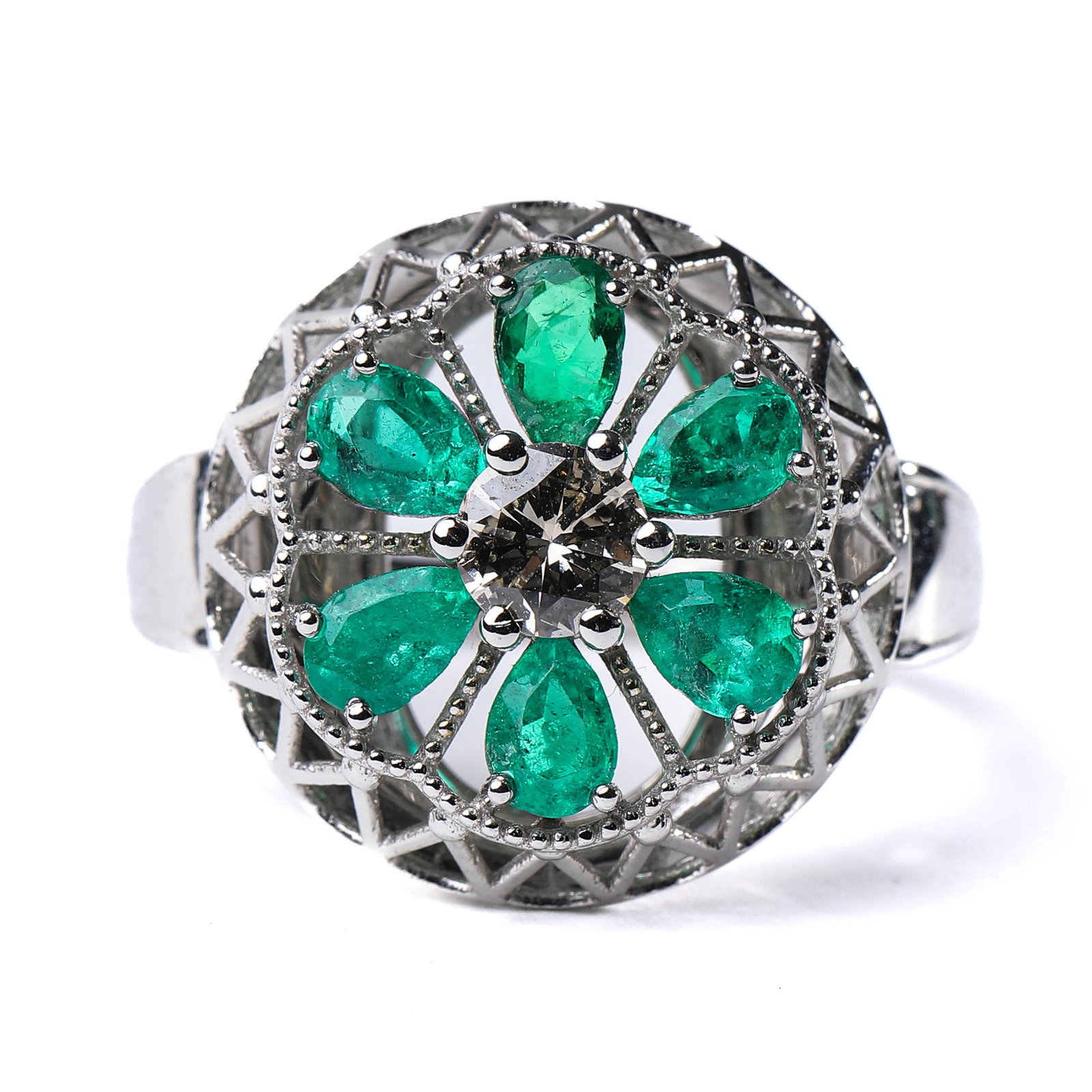 A RETRO PERIOD ITALIAN EMERALD RING.: Crafted in 18K gold, this exquisite ring features a finely hand-made floral design. Six Colombian emeralds are elegantly set in a petal-like arrangement, surrounding a central diamond accent that form