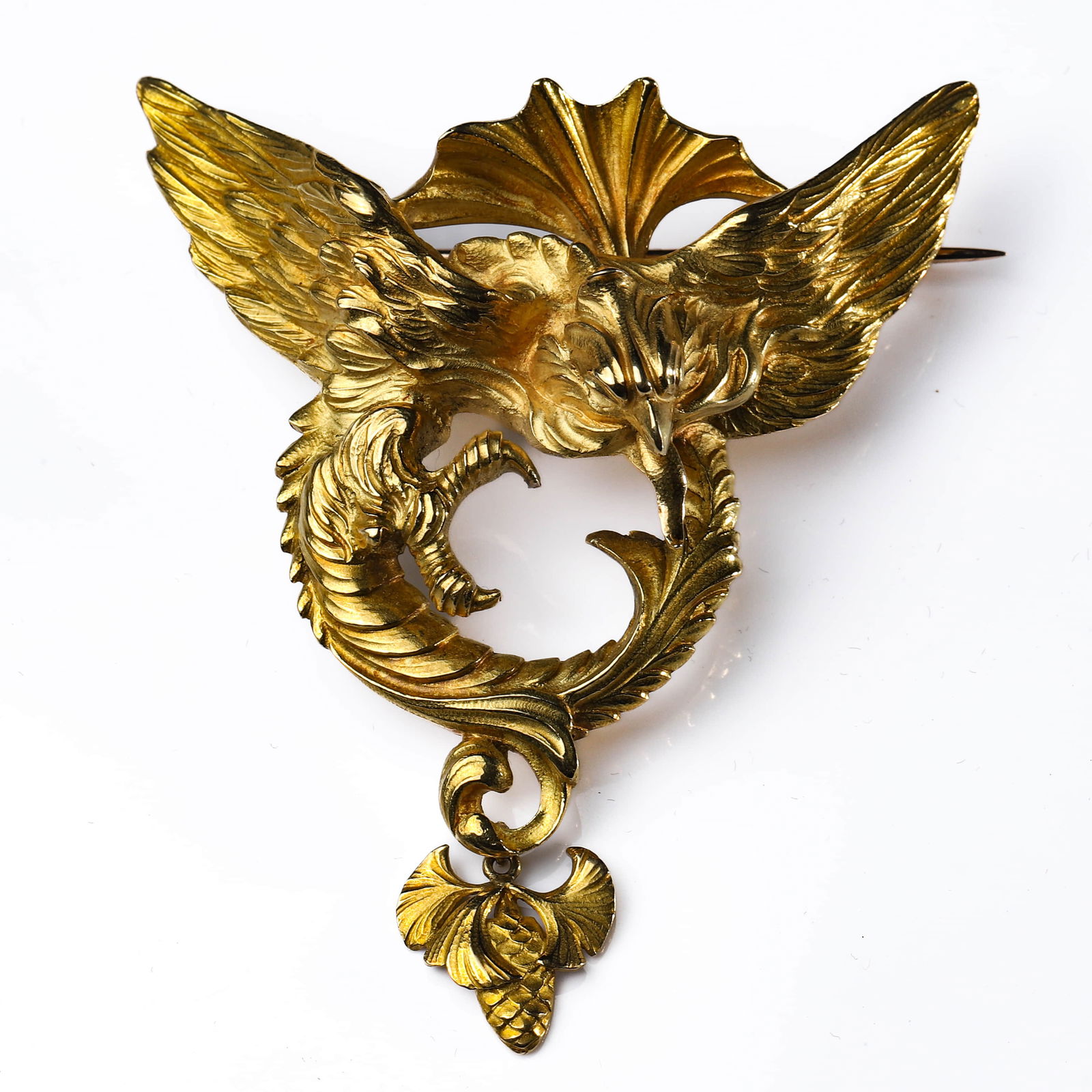 ART NOUVEAU GOLD GRIFFIN BROOCH: Dimensions 2 5/16 × 2 5/16 in. (5.8 × 5.8 cm)Weight: 46.2 g Description A dramatic Art Nouveau gold brooch modeled as a powerful griffin with wings fully extended, its talons grasping a coiled