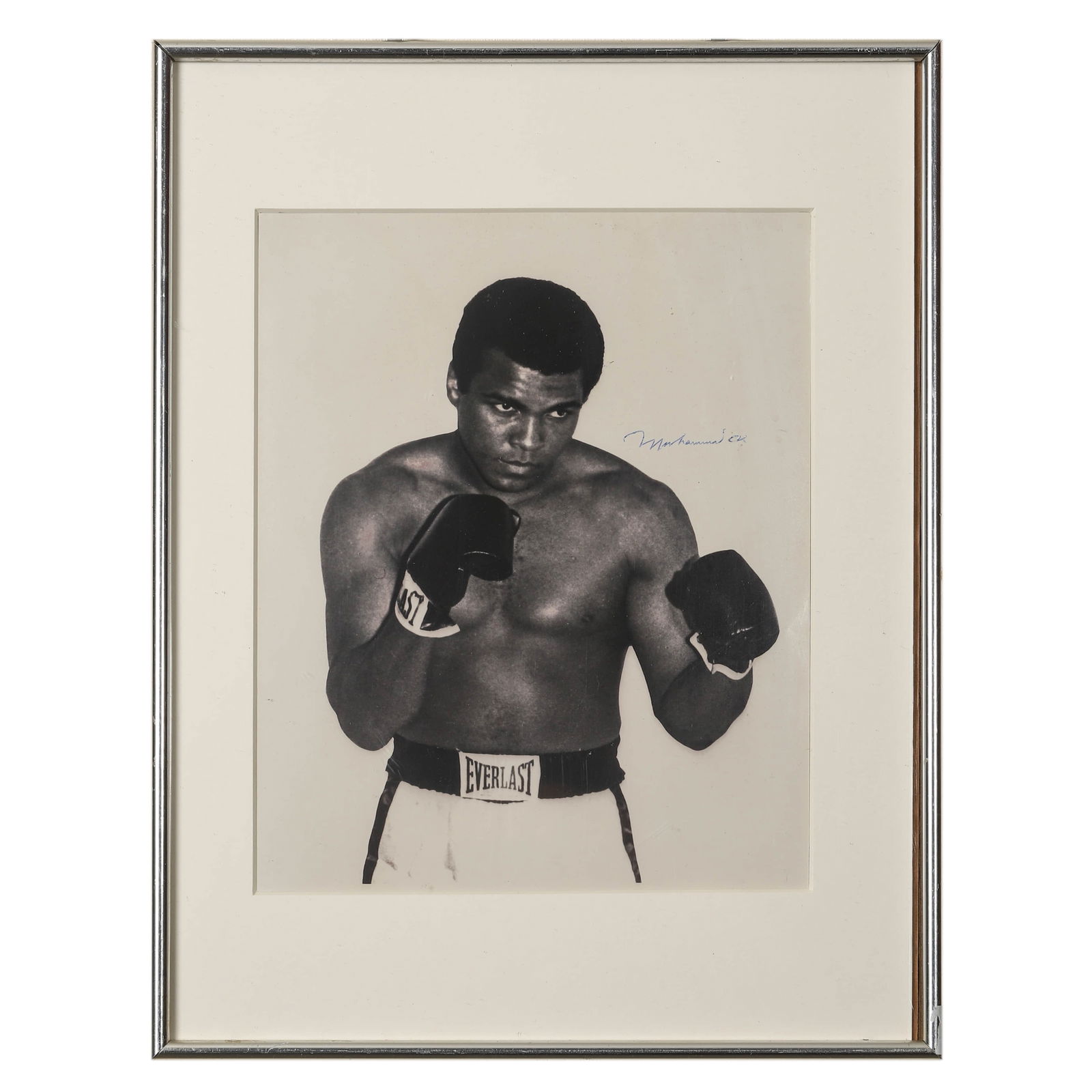PORTRAIT OF MUHAMMAD ALI, CIRCA 1970S: Portrait of Muhammad Ali, circa 1970s Gelatin silver print, signed “Muhammad Ali” in blue ink (upper right) Dimensions: Frame 16 1/2 × 12 3/4 in. (42 × 32.3 cm) Description: A striking
