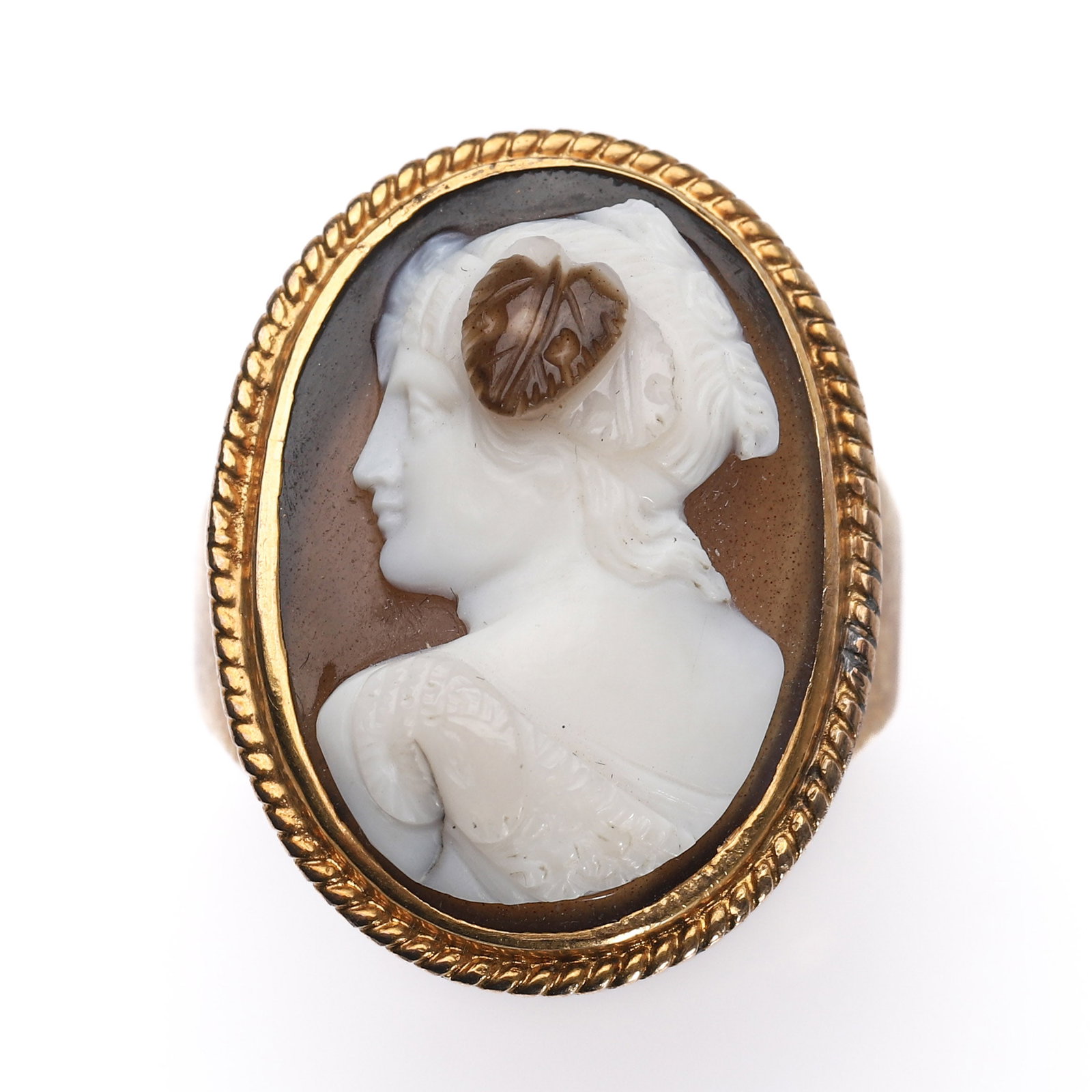 A GOLD RING SET WITH A CAMEO OF A LADY IN PROFILE: Dimensions Inner diameter 3/4 in (18.6 mm); face 13/16 × 9/16 in (21 × 15 mm); weight 8.3 g. Description Finely carved from layered agate, the cameo depicts a classical female figure in left-facing
