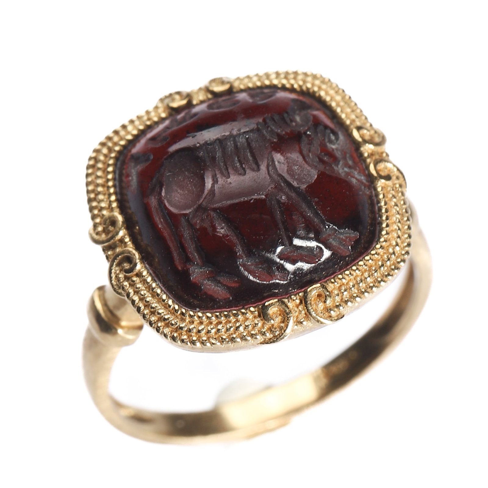 AN ANCIENT INTAGLIO GARNET GOLD RING: Dimensions Inner diameter: 21/32 in (16.7 mm); Weight: 5.7 g. Description A refined ring set with an ancient dark red garnet intaglio, engraved with a quadruped animal rendered in a stylized