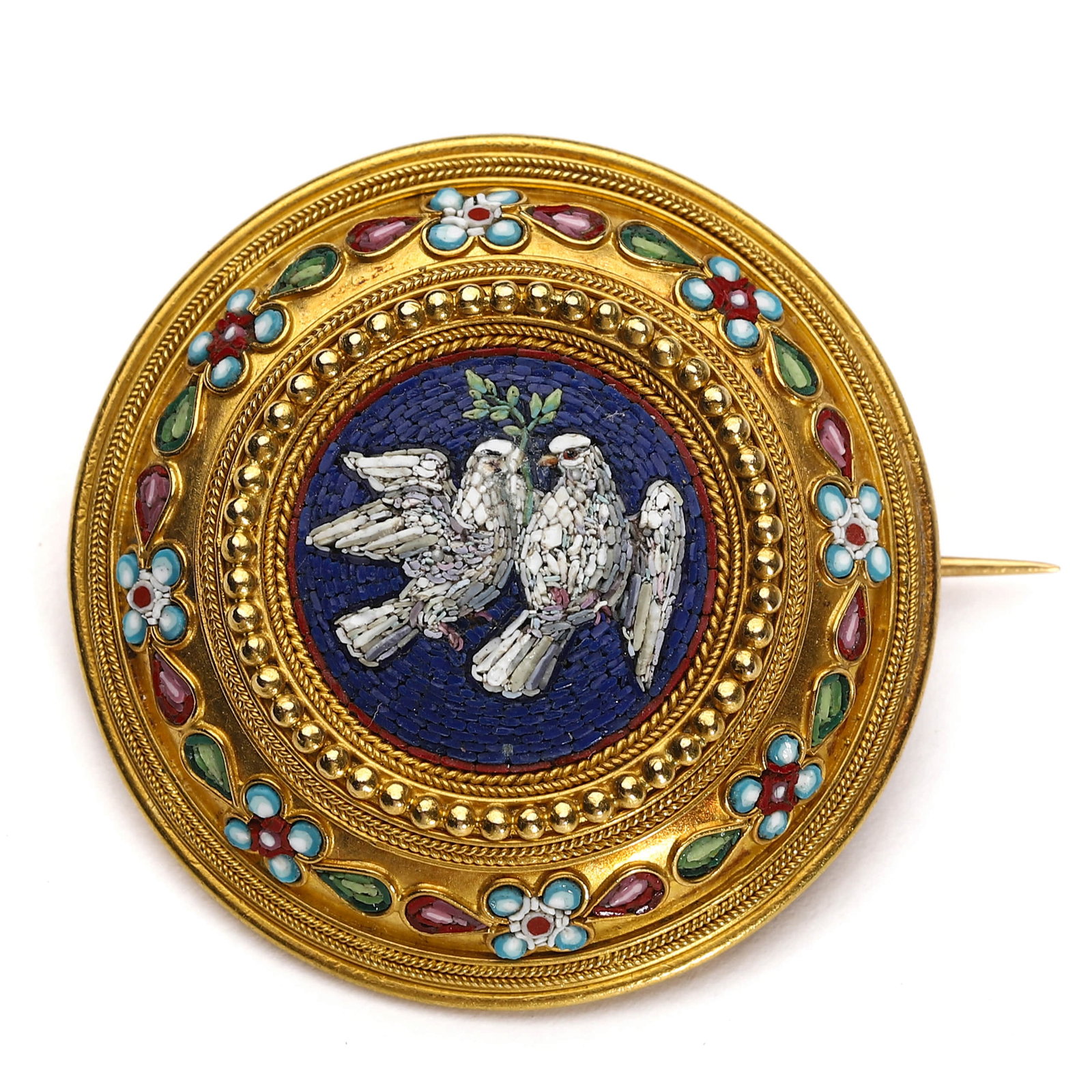 MICROMOSAIC GOLD BROOCH WITH DOVES AND FLORAL DECORATION: Dimensions: Diameter: 1 7/16 in. (36 mm); Weight: 14 g Description: A fine circular micromosaic brooch in gold, centering a pair of white doves perched together, set against a deep blue ground. The mi