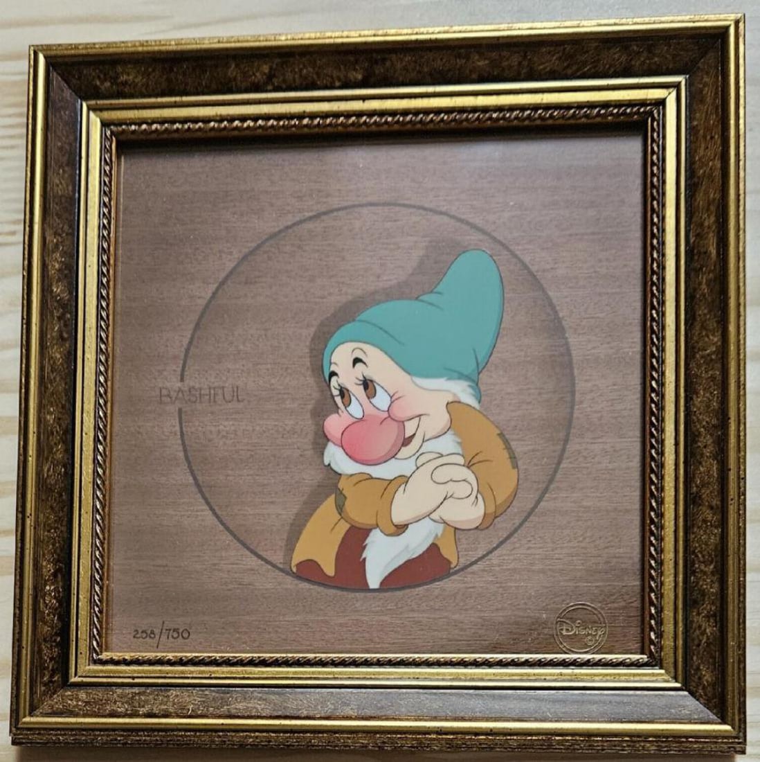 Disney, 'Snow White - Bashful', Limited Edition Courvoisier: Studio: Walt Disney Title: 'Bashful' from Snow White and the Seven Dwarfs Medium: hand-painted and hand-inked with a wood veneer background Date: 1997 Character: Bashful Edition: 258/750 Framed: Yes S