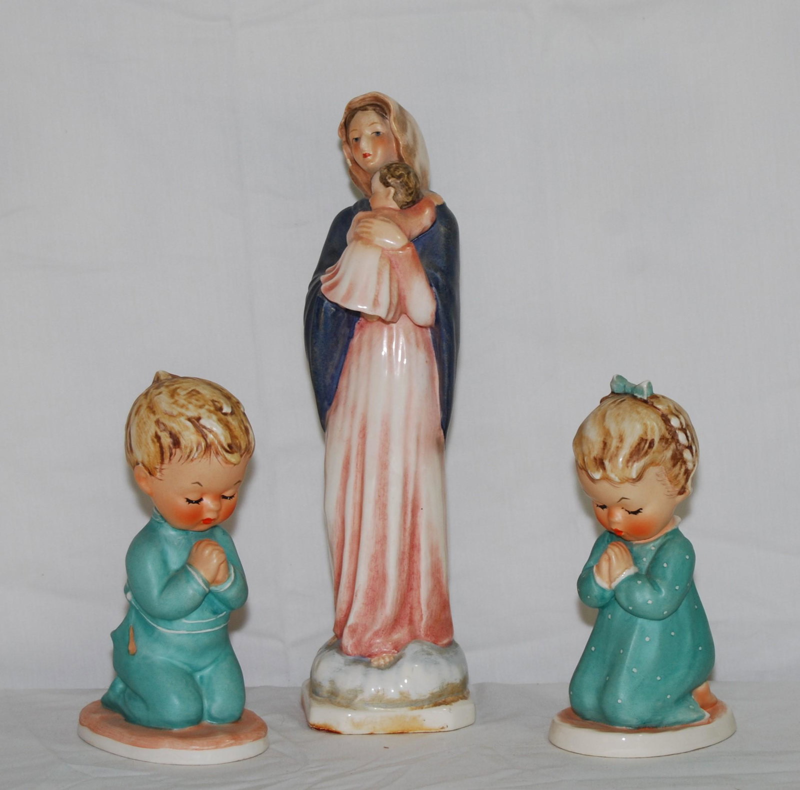 Three Hummel Figures: Three Hummel Figures. Including Madonna and Child marked with the Hummel V and Stylized Bee and “HM116”, 9 ½”t. Also, two praying figures: a boy and a girl, the girl is marked &
