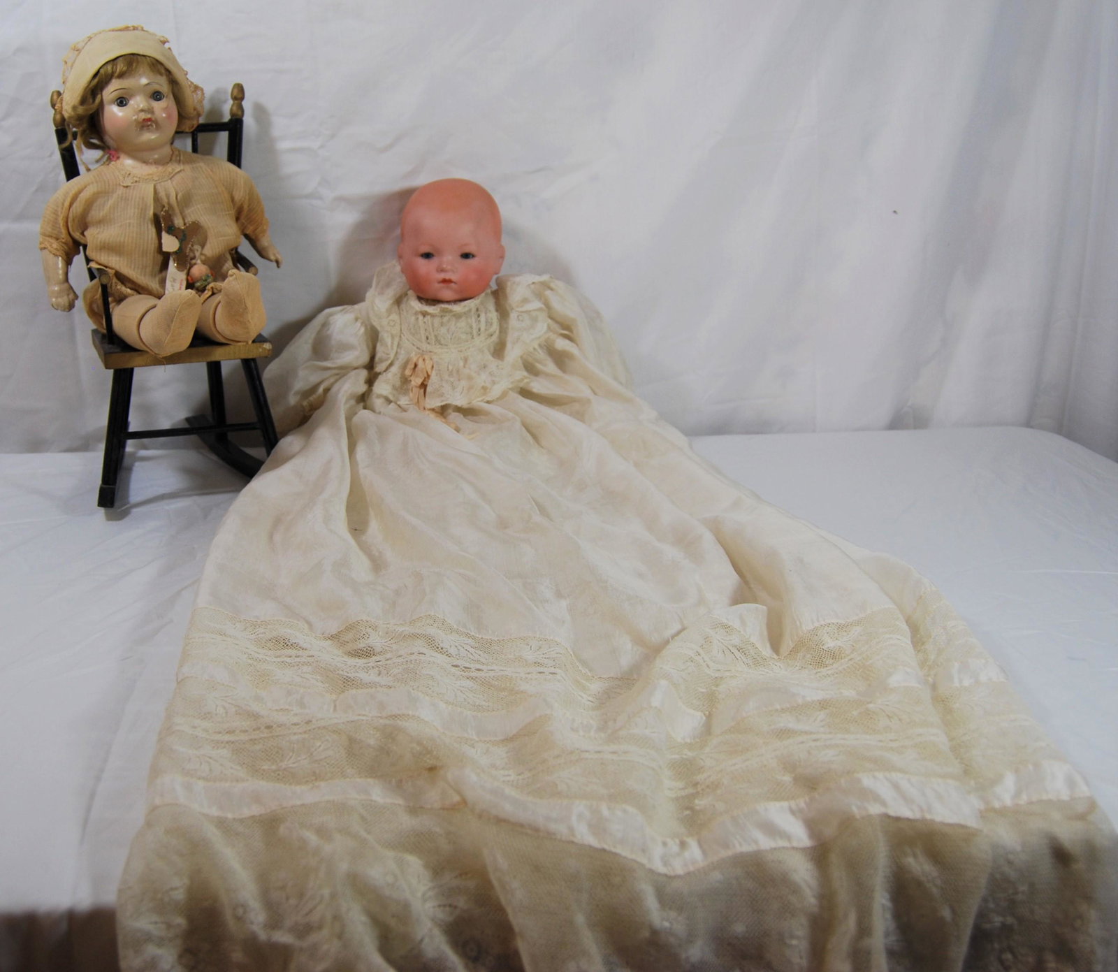 Two Vintage Bisque Dolls-inc. Armand Marseille: Two Vintage Bisque Dolls, including Armand Marseille Doll, plus a Rocking Chair. The Armand Marseille baby doll is dressed in a vintage long Christening gown, doll has bisque head, soft body, composit